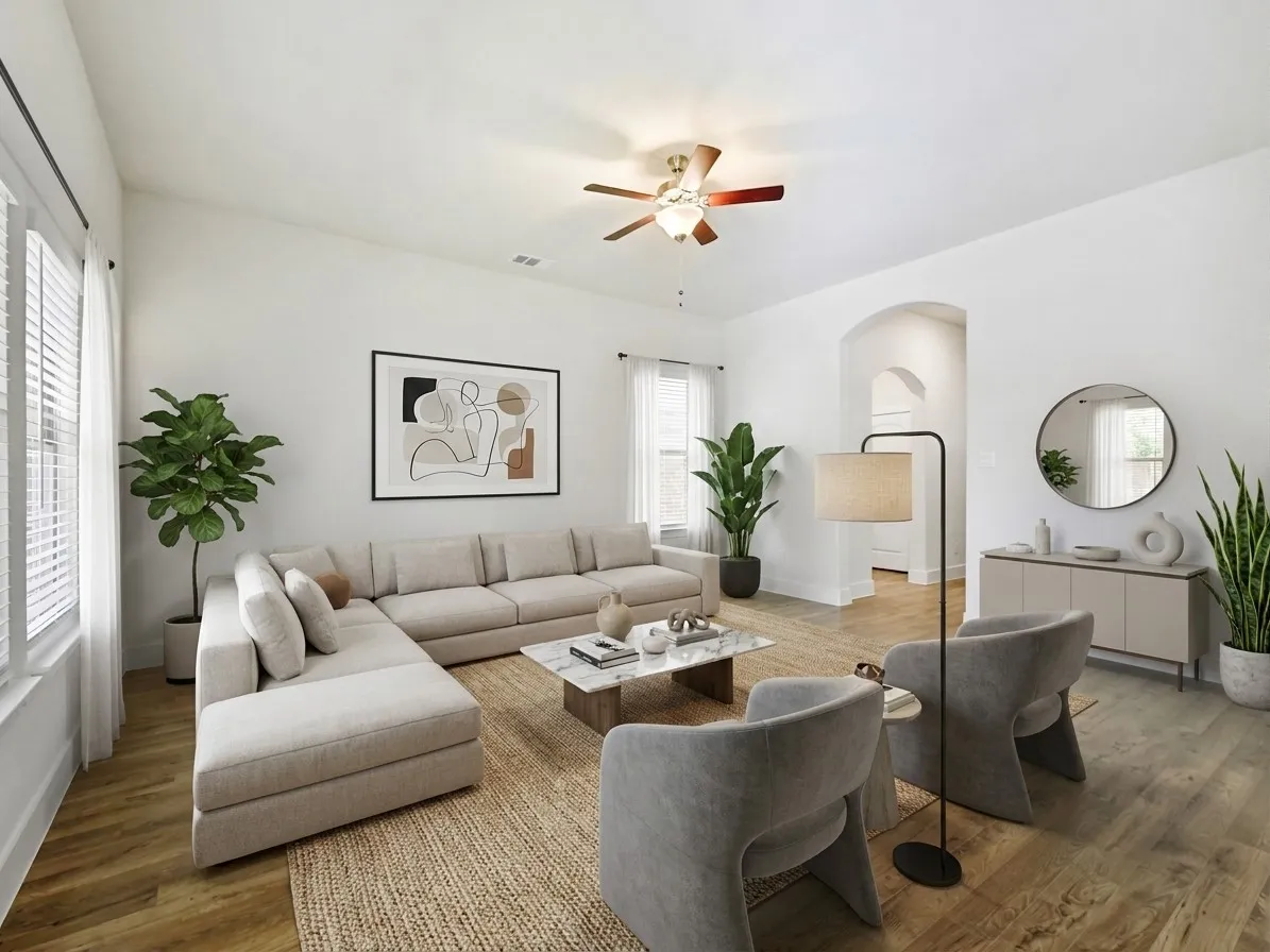 Spacious living area featuring wood-finish flooring, white walls, and a ceiling fan with integrated lighting