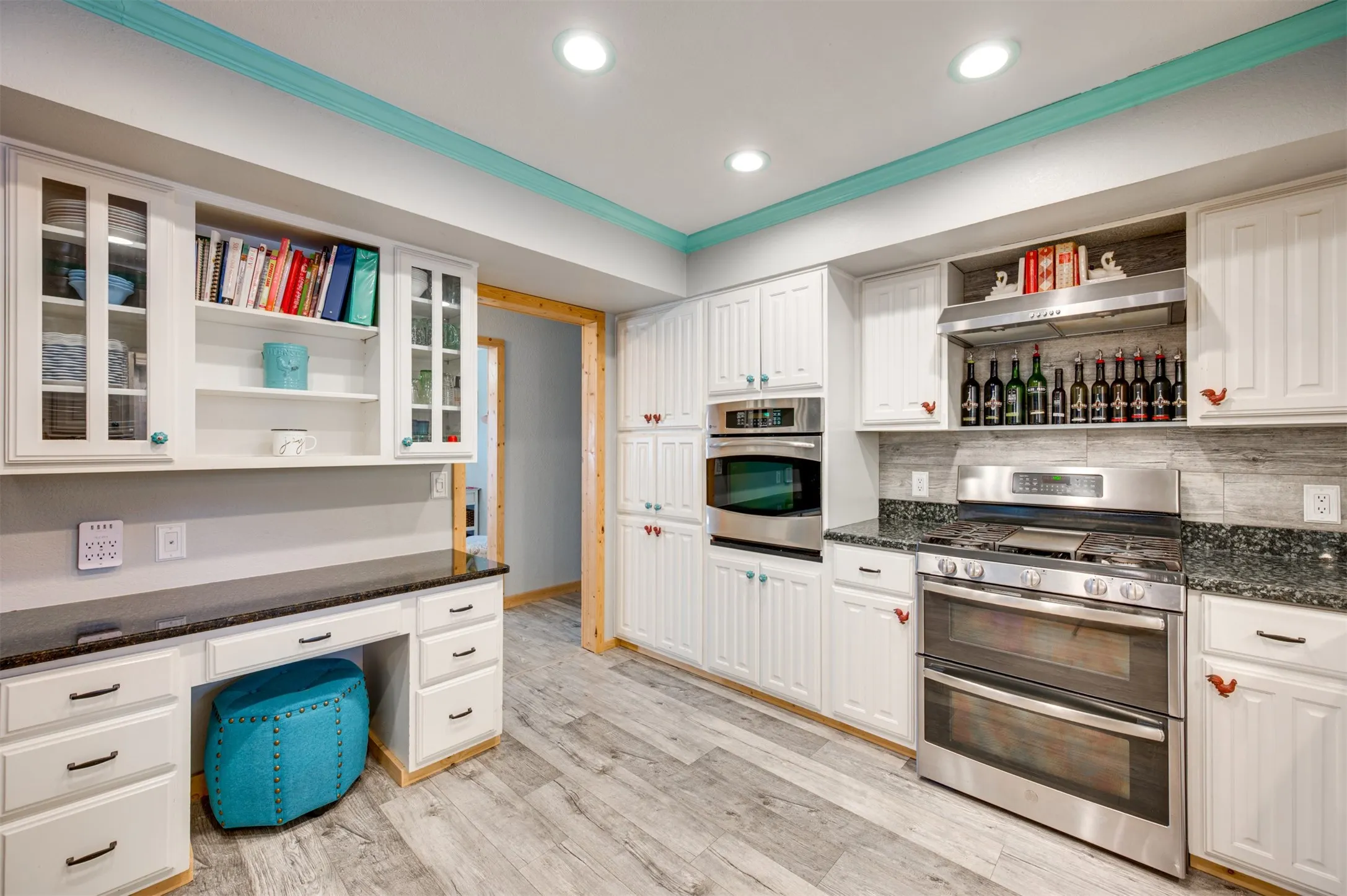 Desk area in kitchen with shelving above