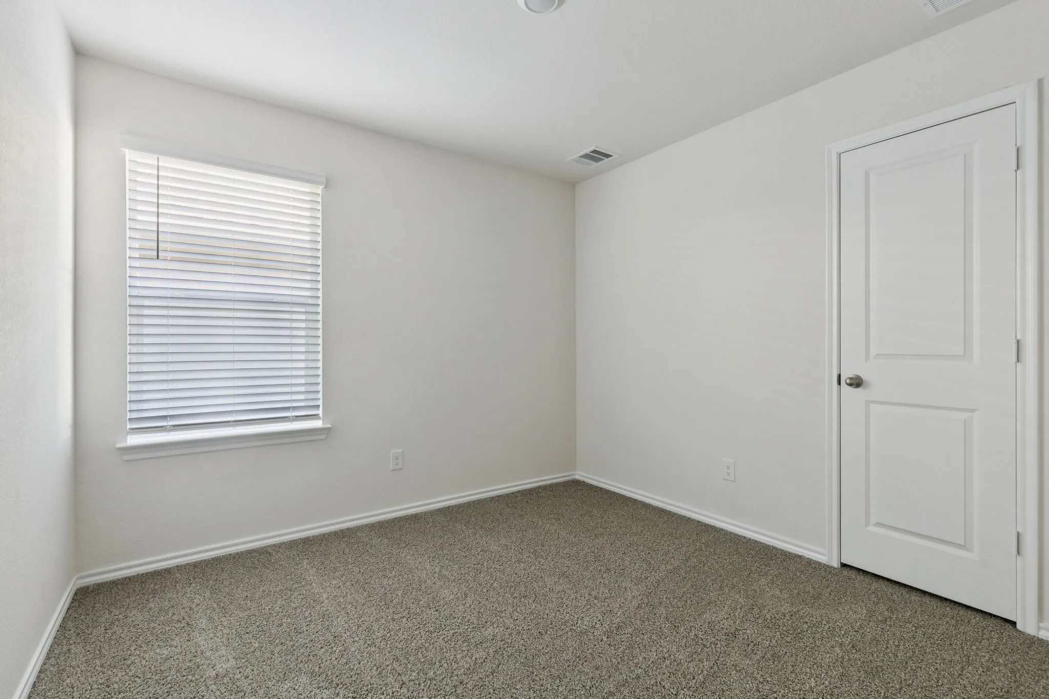 Carpeted spare room featuring baseboards