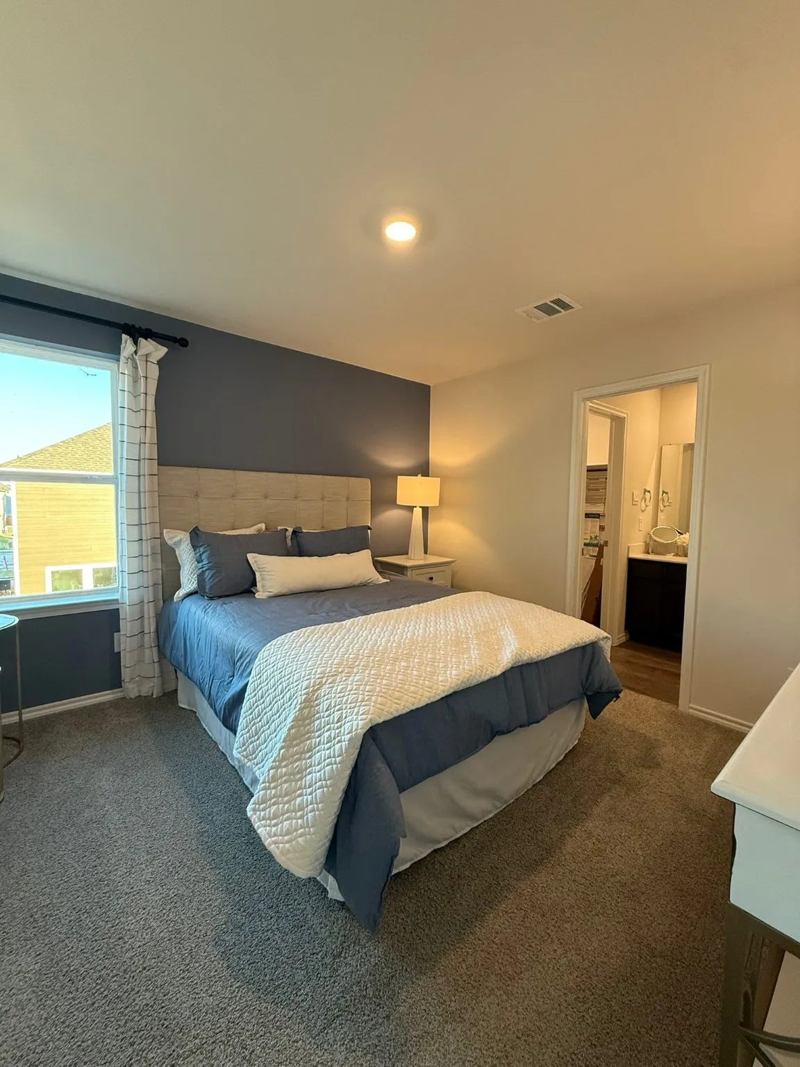Carpeted bedroom featuring ensuite bath and baseboards
