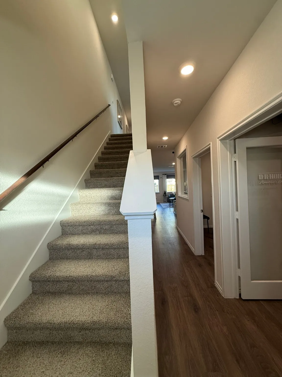 Stairs with wood finished floors and recessed lighting