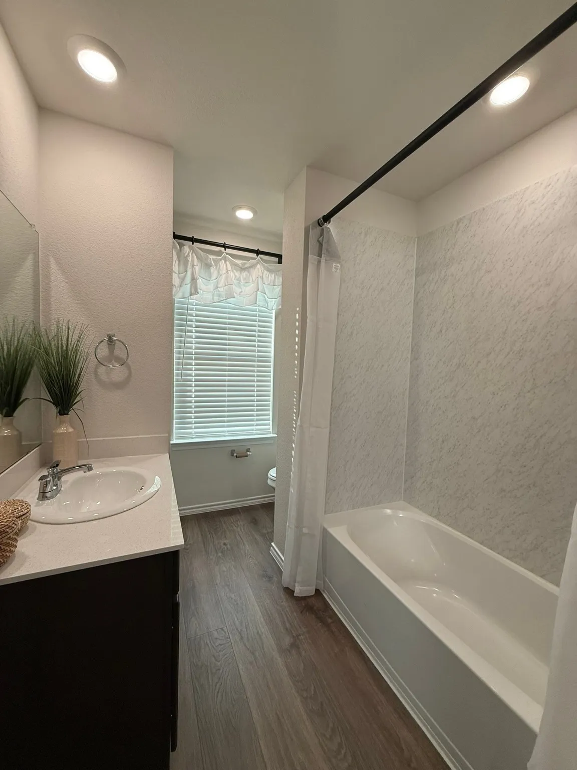 Bathroom with dark wood-style floors, vanity, shower / bathtub combination with curtain, and recessed lighting