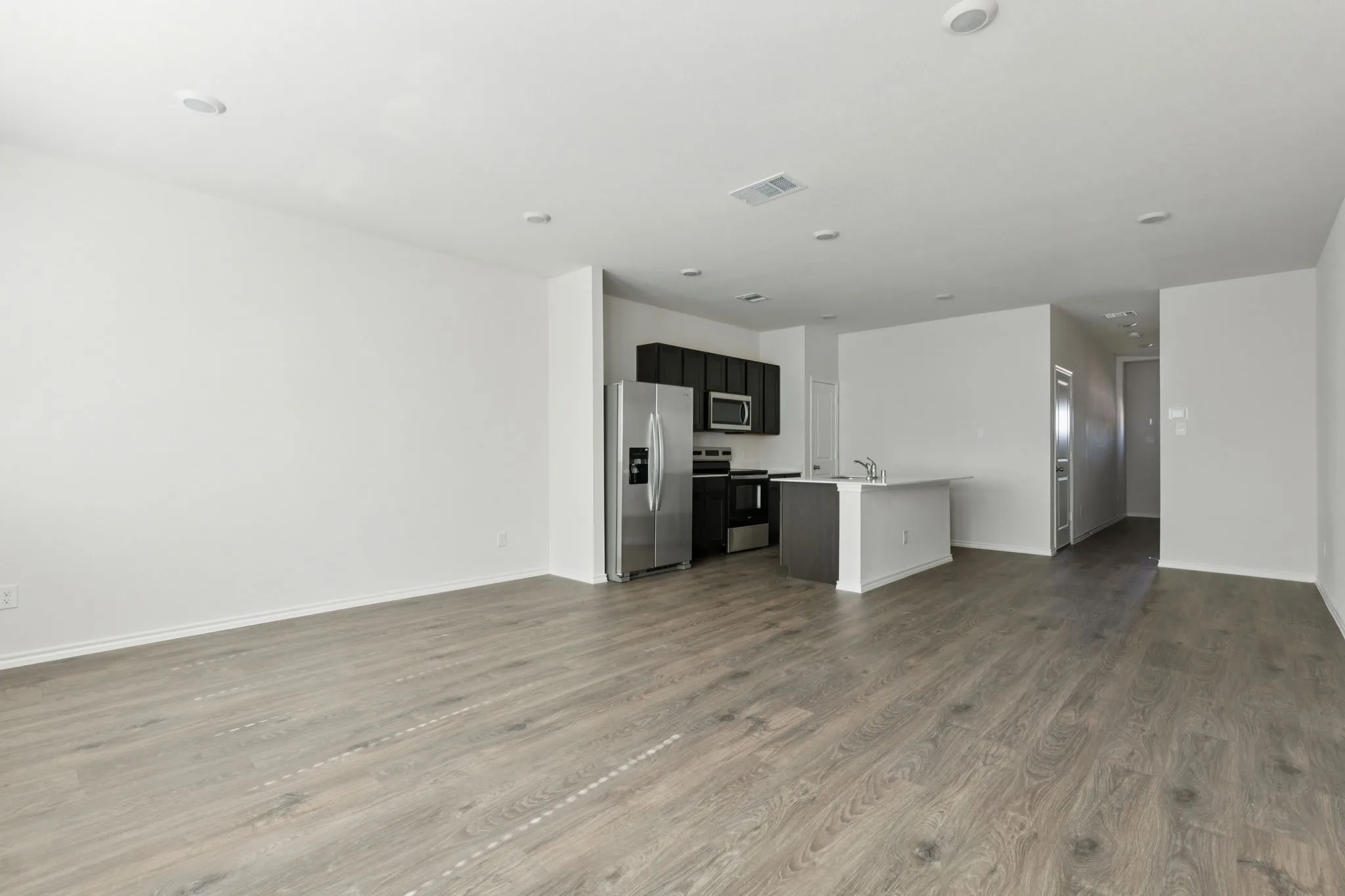 Unfurnished living room with dark wood-style flooring and recessed lighting