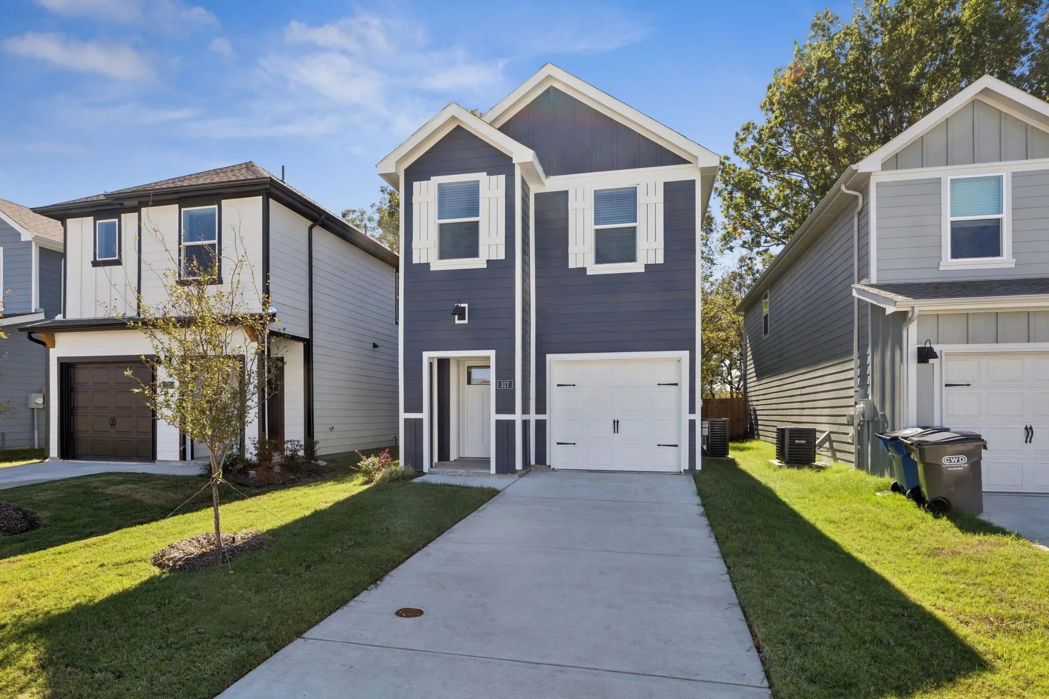 View of front of property with board and batten siding, a front lawn, driveway, and a garage