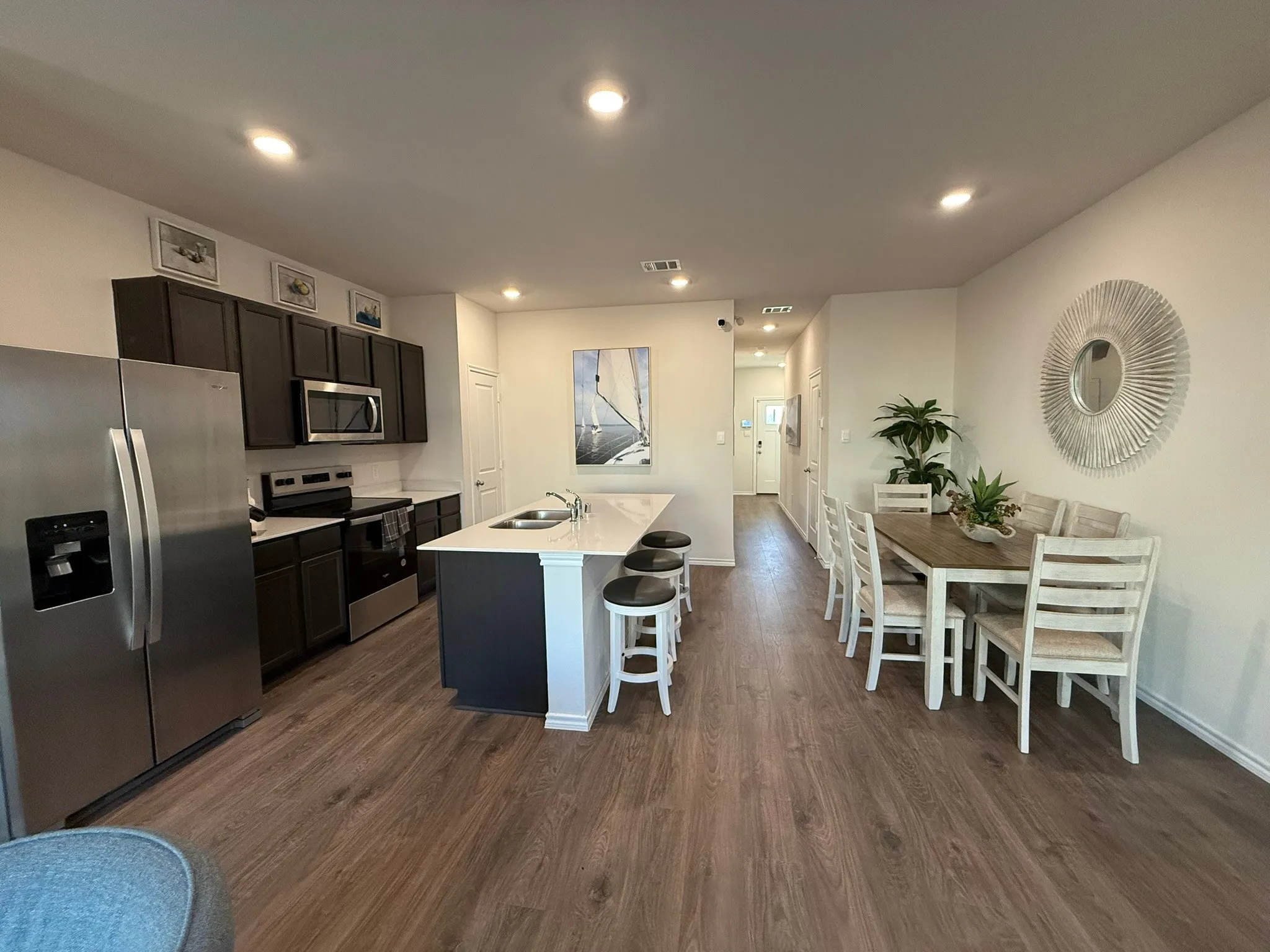 Kitchen with stainless steel appliances, dark wood-style flooring, a center island with sink, recessed lighting, and a kitchen breakfast bar