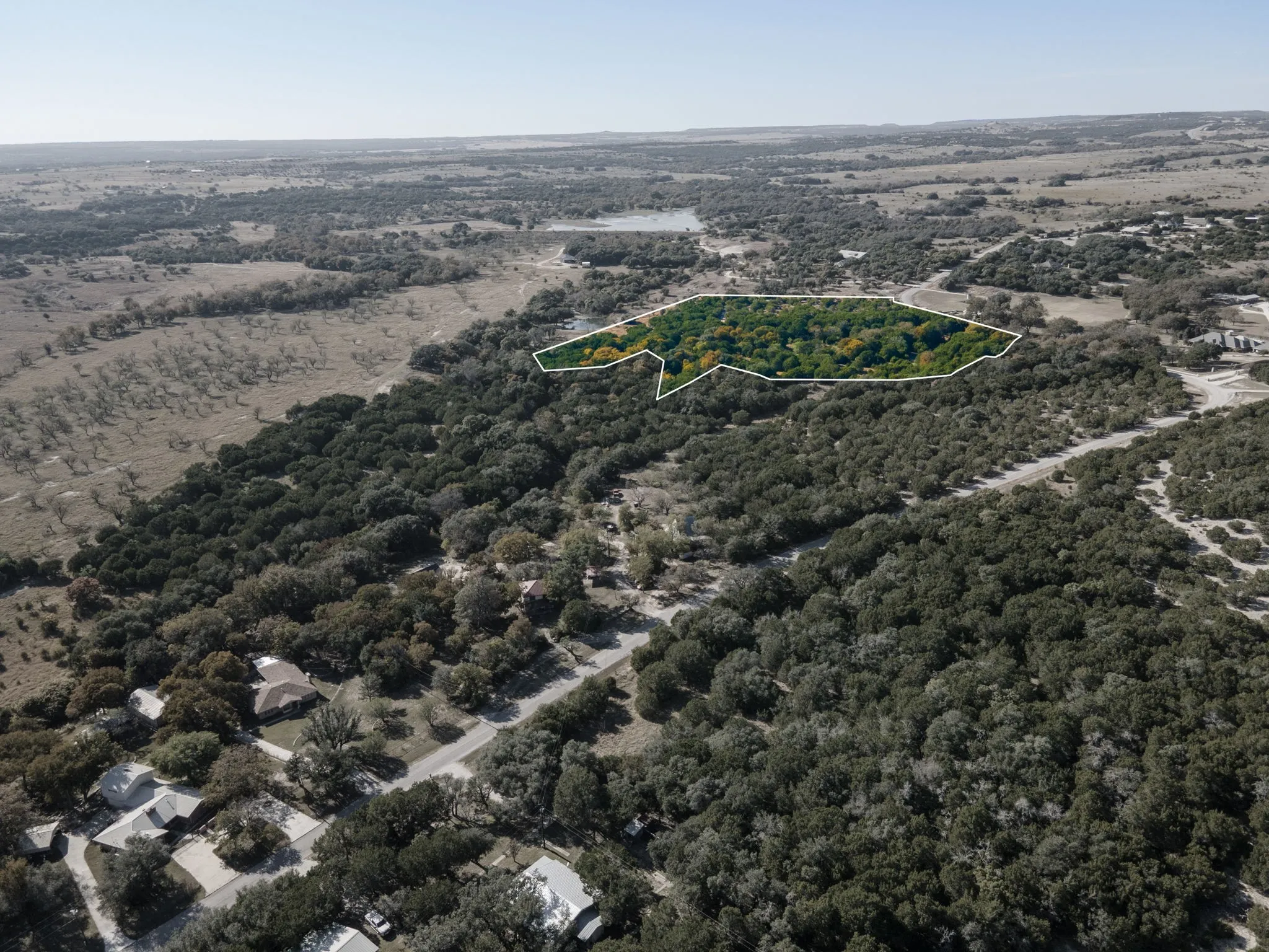 Aerial view of property and surrounding area with a heavily wooded area and property boundaries highlighted