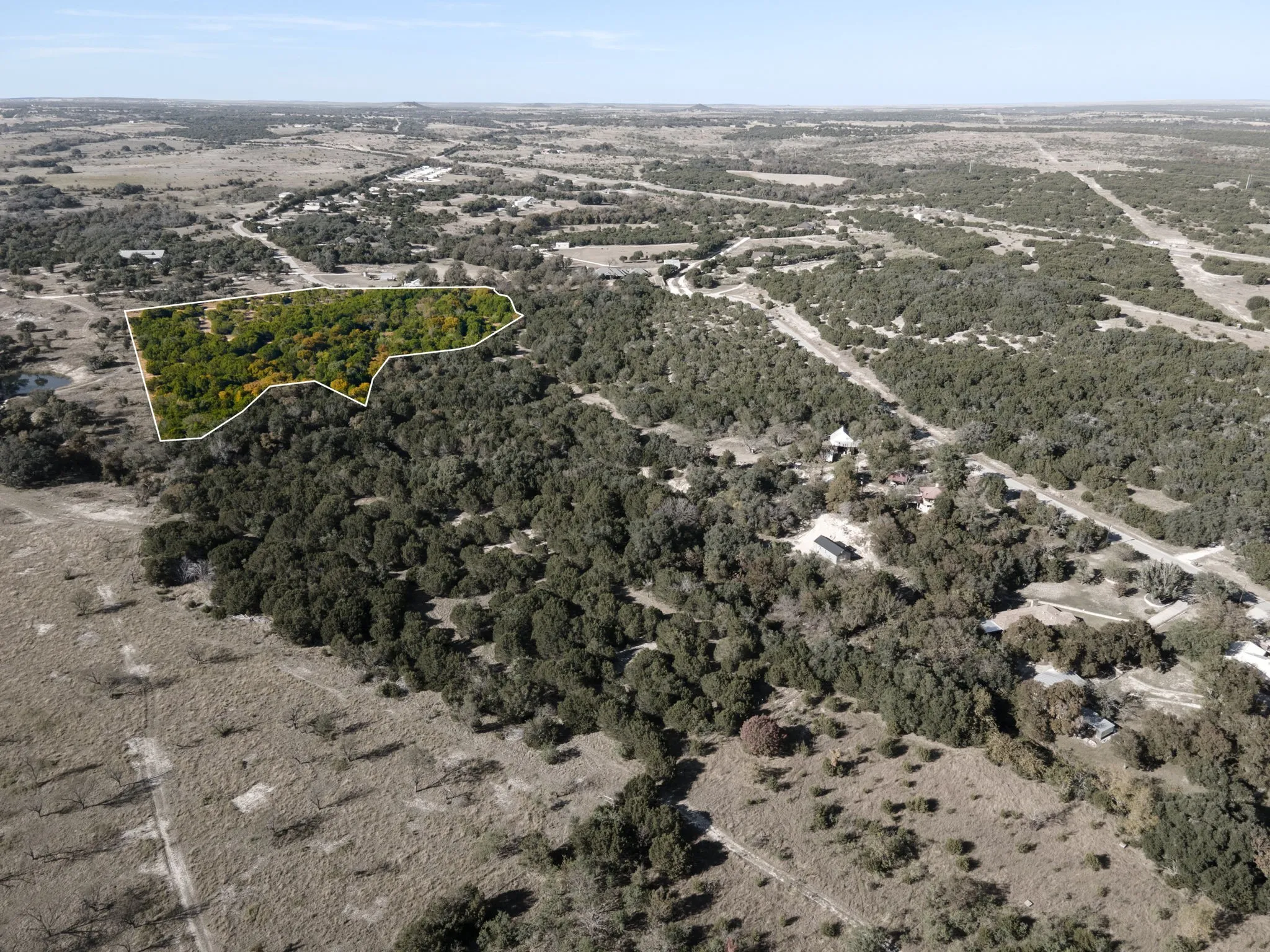 Aerial overview of property's location with property parcel outlined and a heavily wooded area