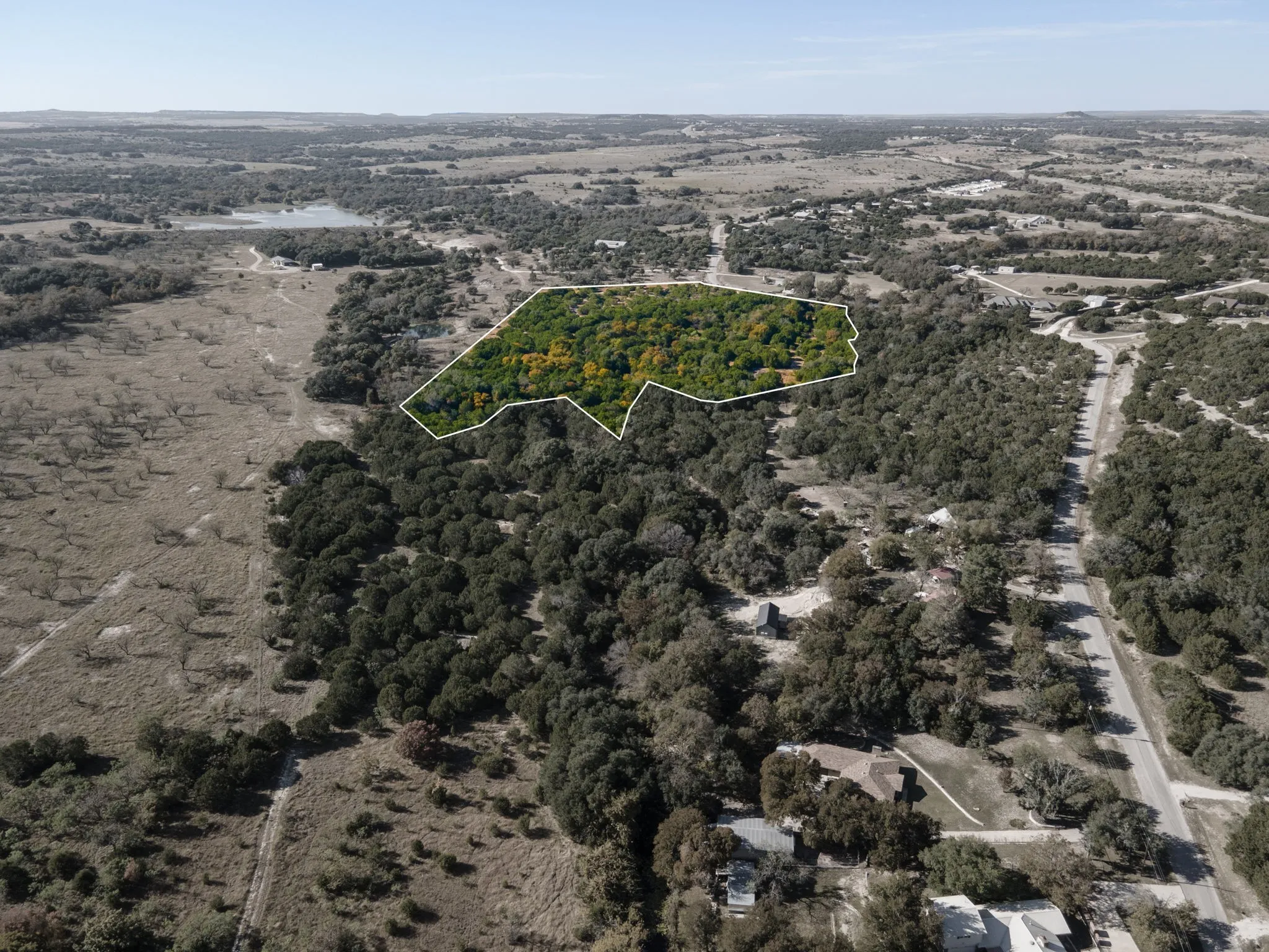 Aerial view of property's location featuring property parcel outlined and a forest