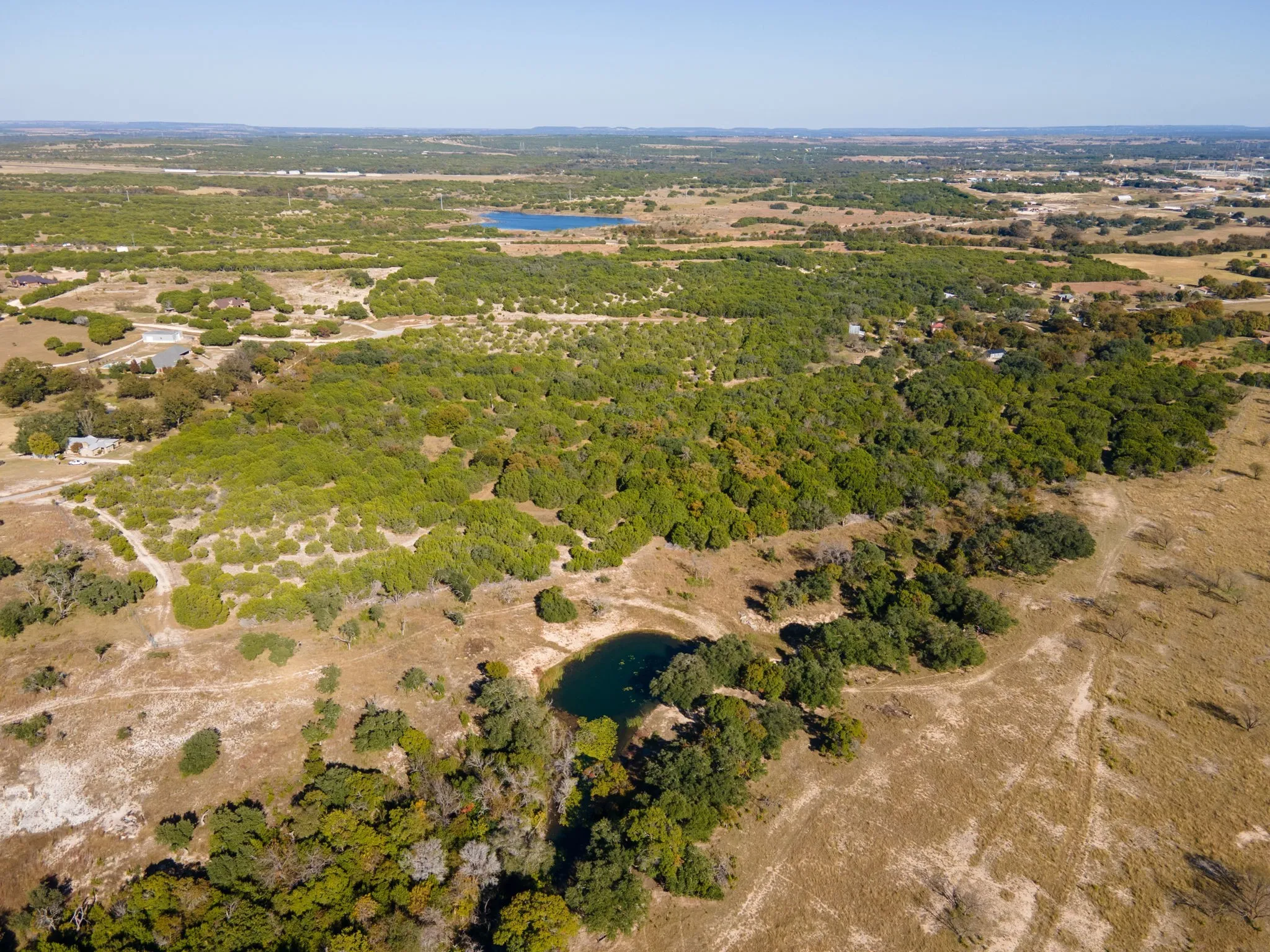 Aerial overview of property's location with a nearby body of water and a forest