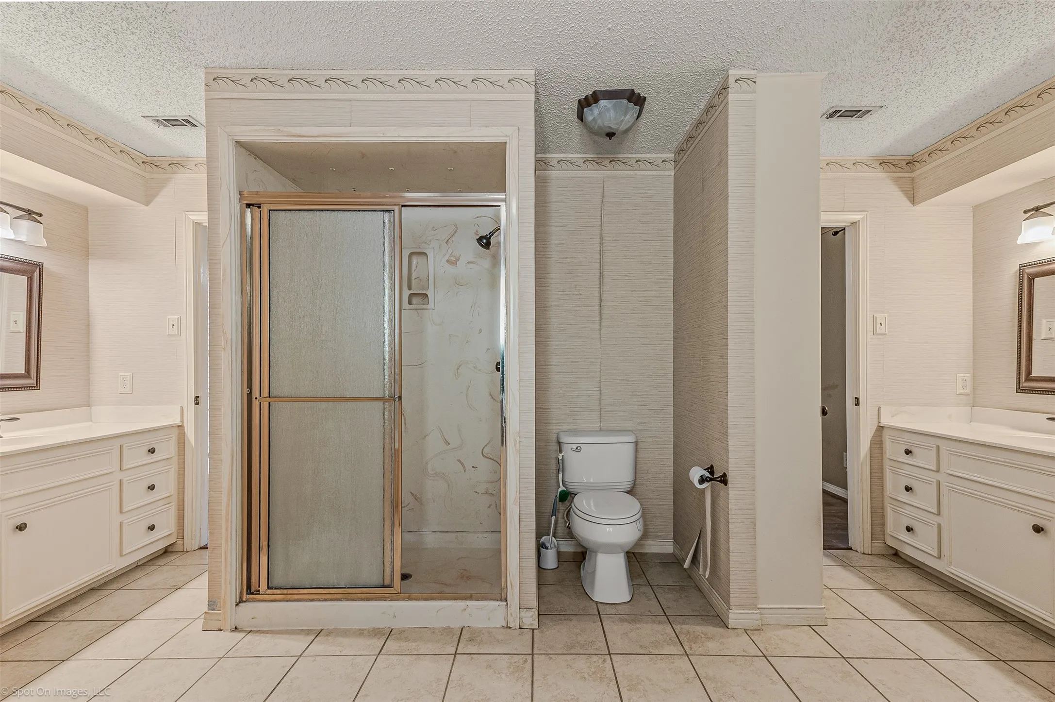 Full bath featuring vanity, light tile patterned floors, a textured ceiling, and a stall shower