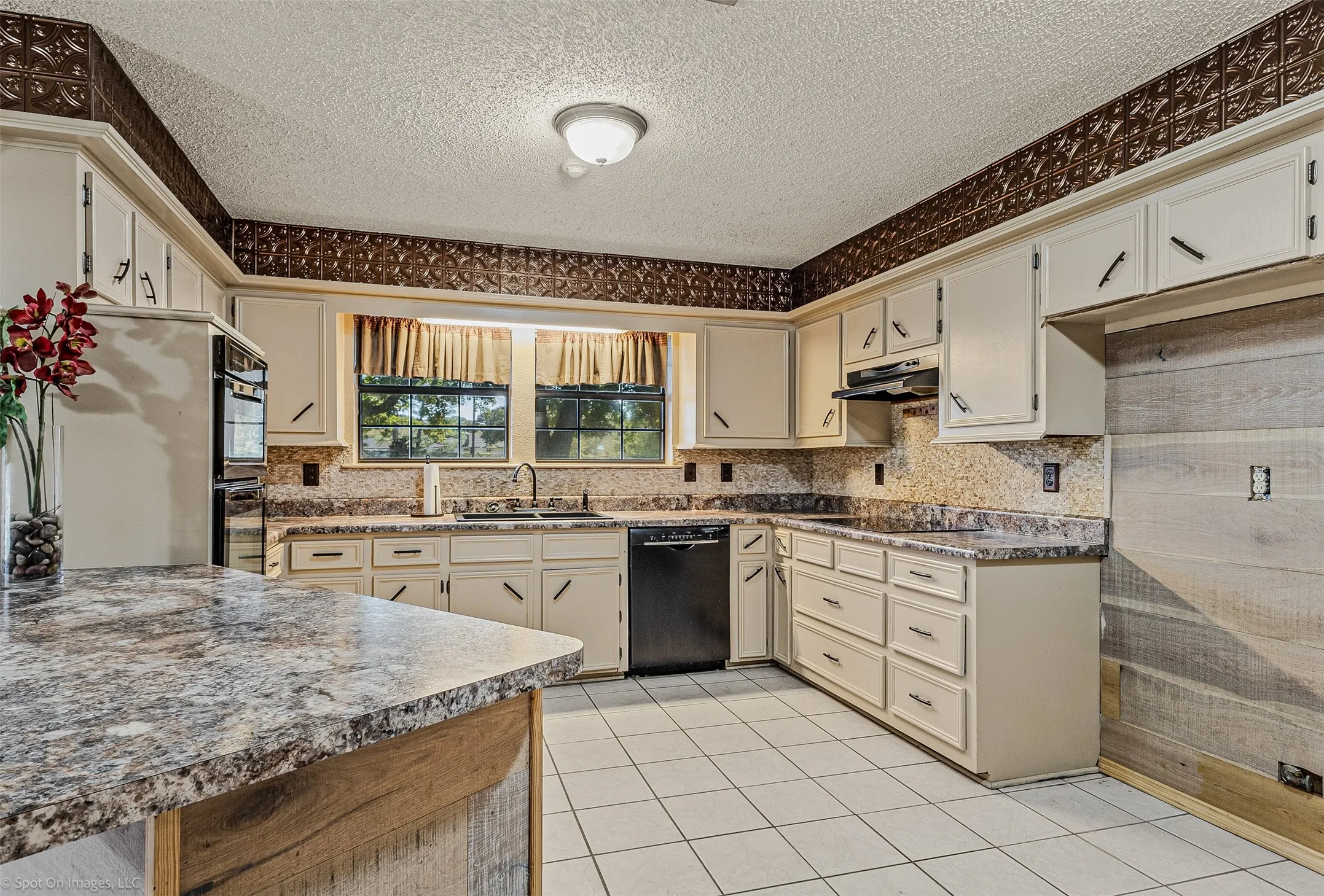 Kitchen featuring black appliances, light tile patterned floors, a textured ceiling, tasteful backsplash, and dark countertops