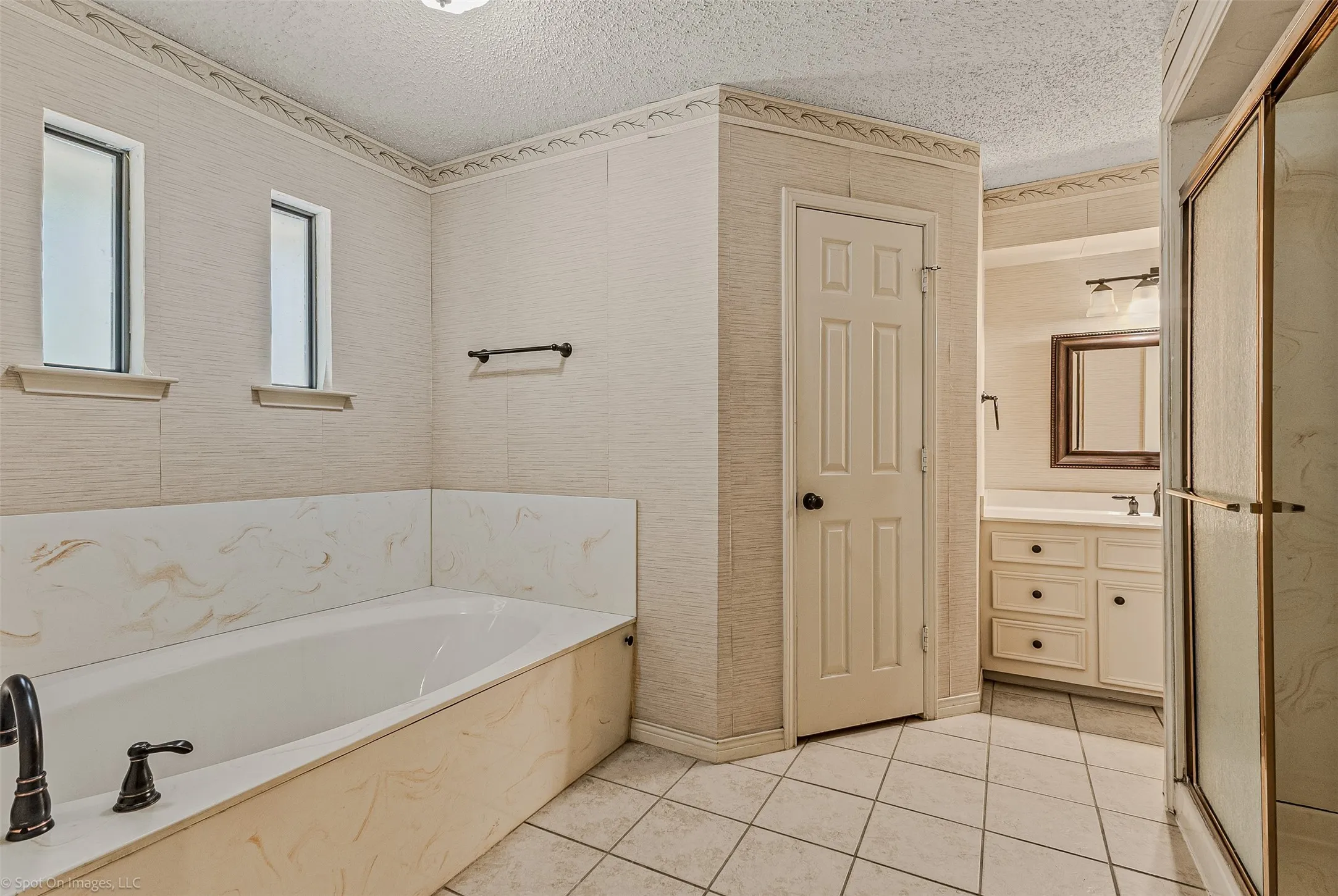 Full bathroom with vanity, a shower stall, light tile patterned flooring, a textured ceiling, and a bath