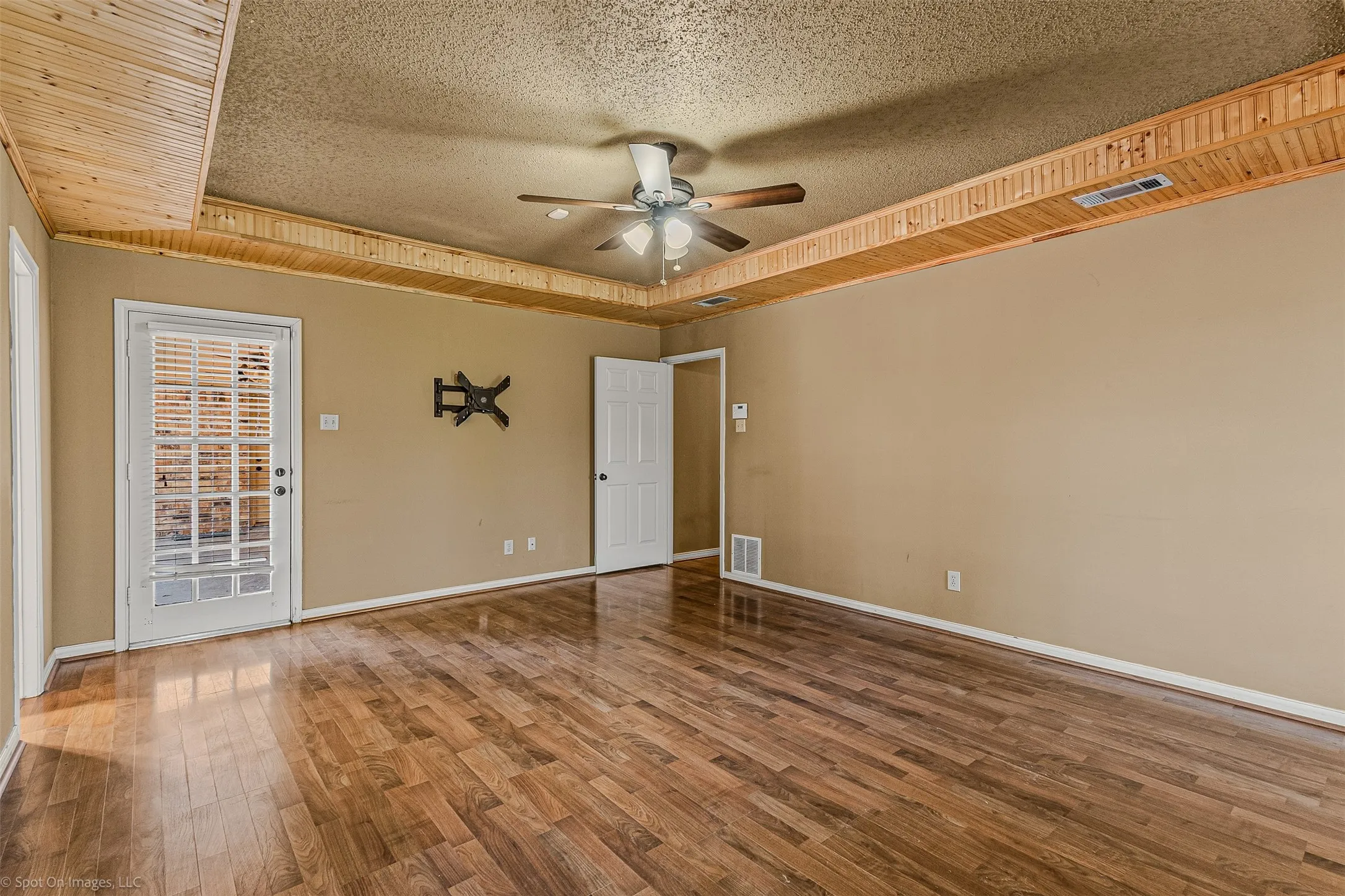 Spare room featuring a textured ceiling, wood finished floors, ceiling fan, and a raised ceiling