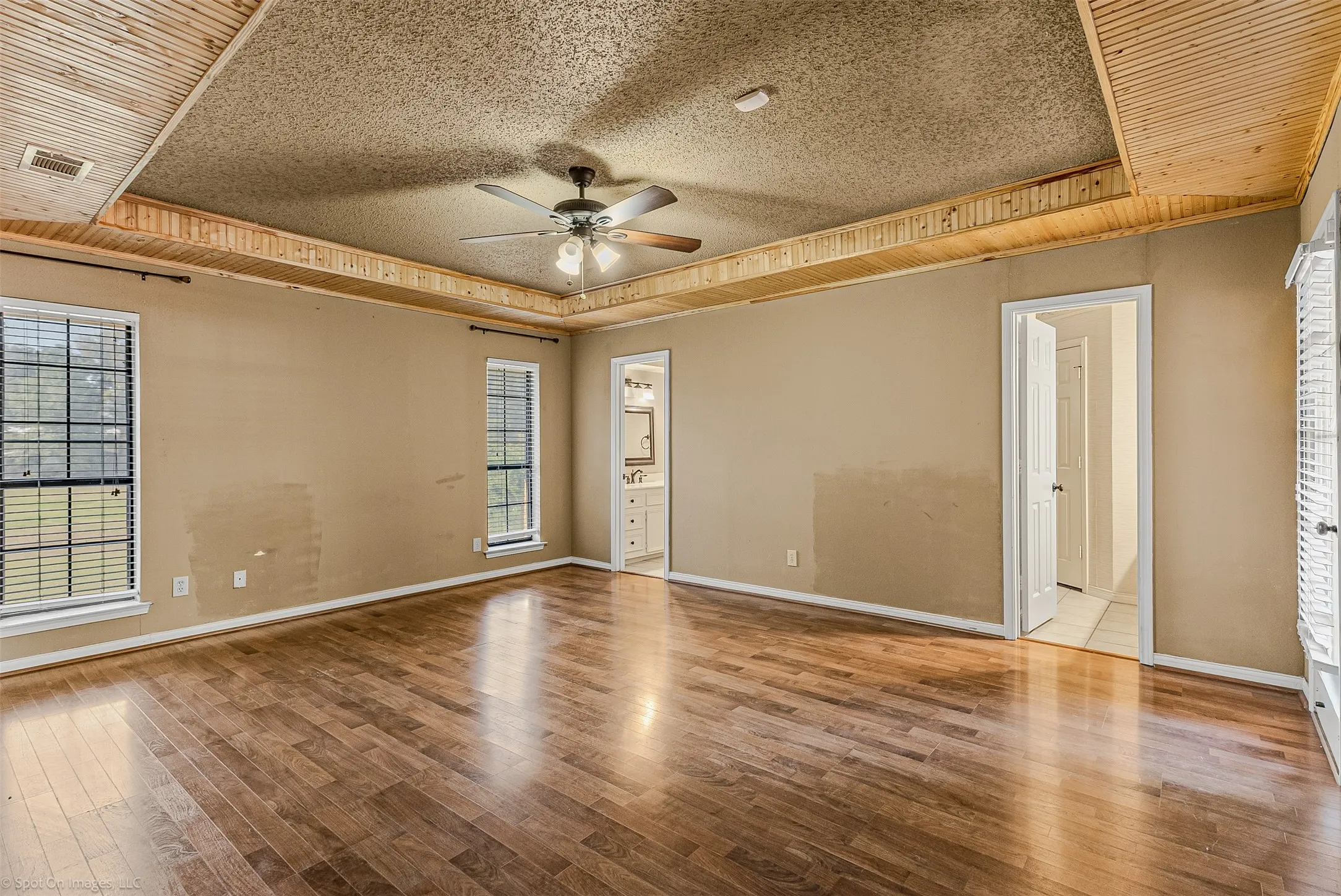 Empty room with a tray ceiling, healthy amount of natural light, a textured ceiling, and light wood-style flooring