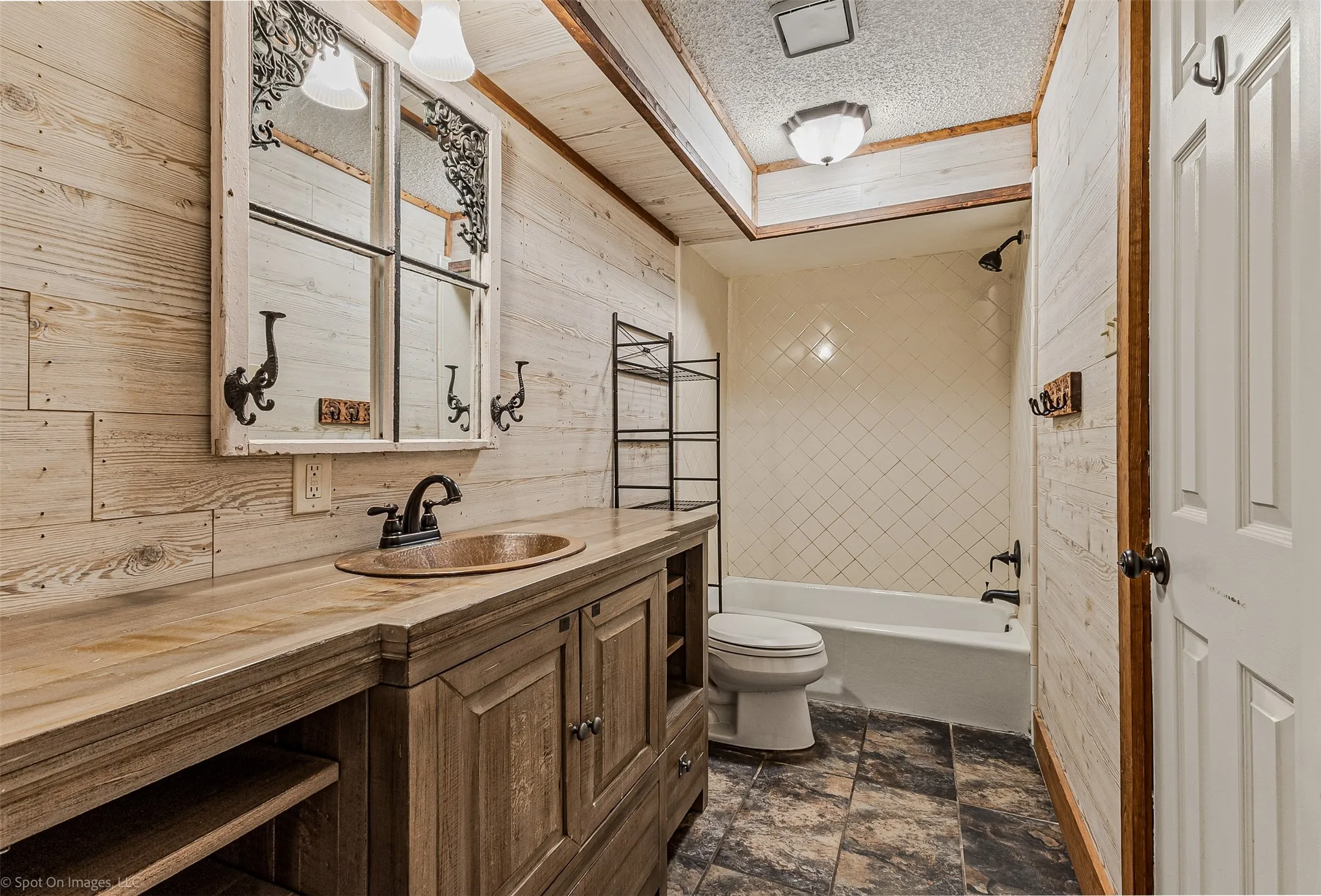 Full bathroom featuring tub / shower combination, vanity, a textured ceiling, and wood walls