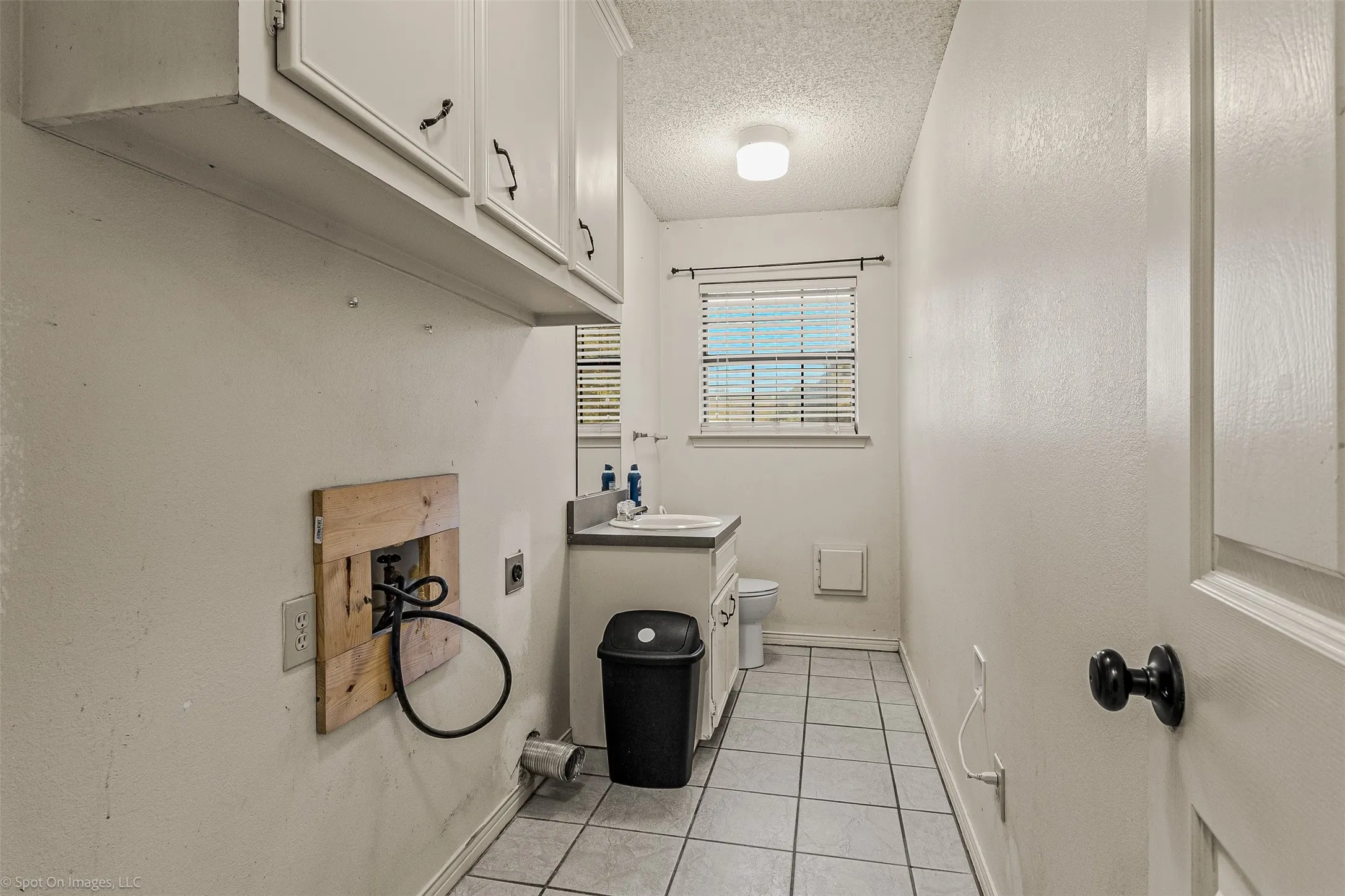 Washroom with light tile patterned floors, hookup for a washing machine, a textured ceiling, and electric dryer hookup