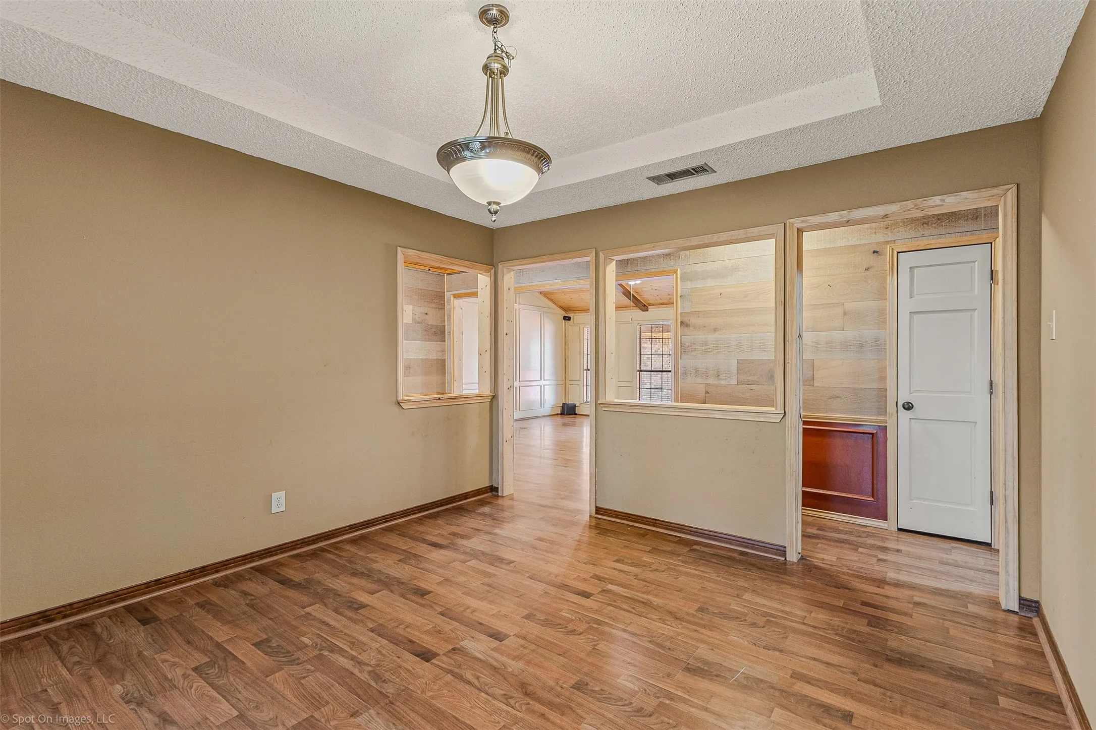 Spare room with a textured ceiling, wood finished floors, and a raised ceiling
