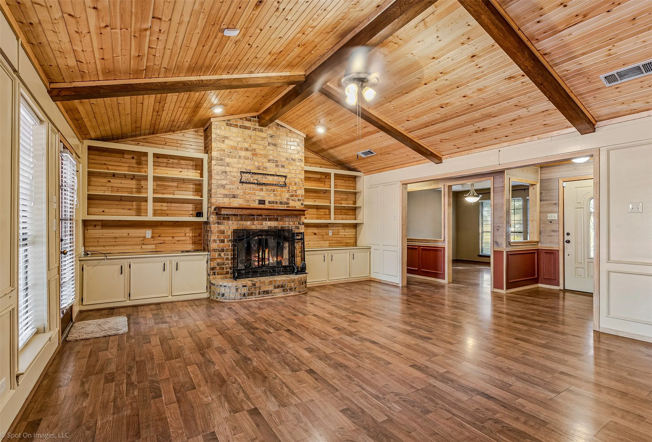 Unfurnished living room with wood finished floors, a fireplace, ceiling fan, wood ceiling, and built in shelves