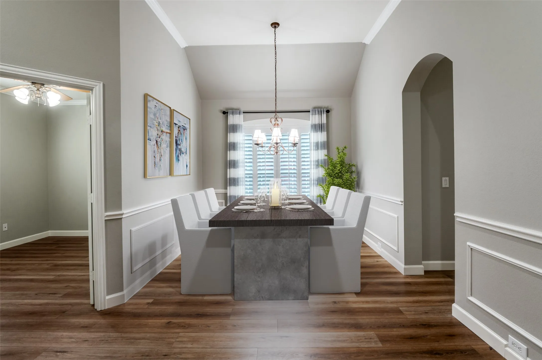 Virtual Staged Dining area with lofted ceiling, dark wood-style floors, a chandelier, and wainscoting