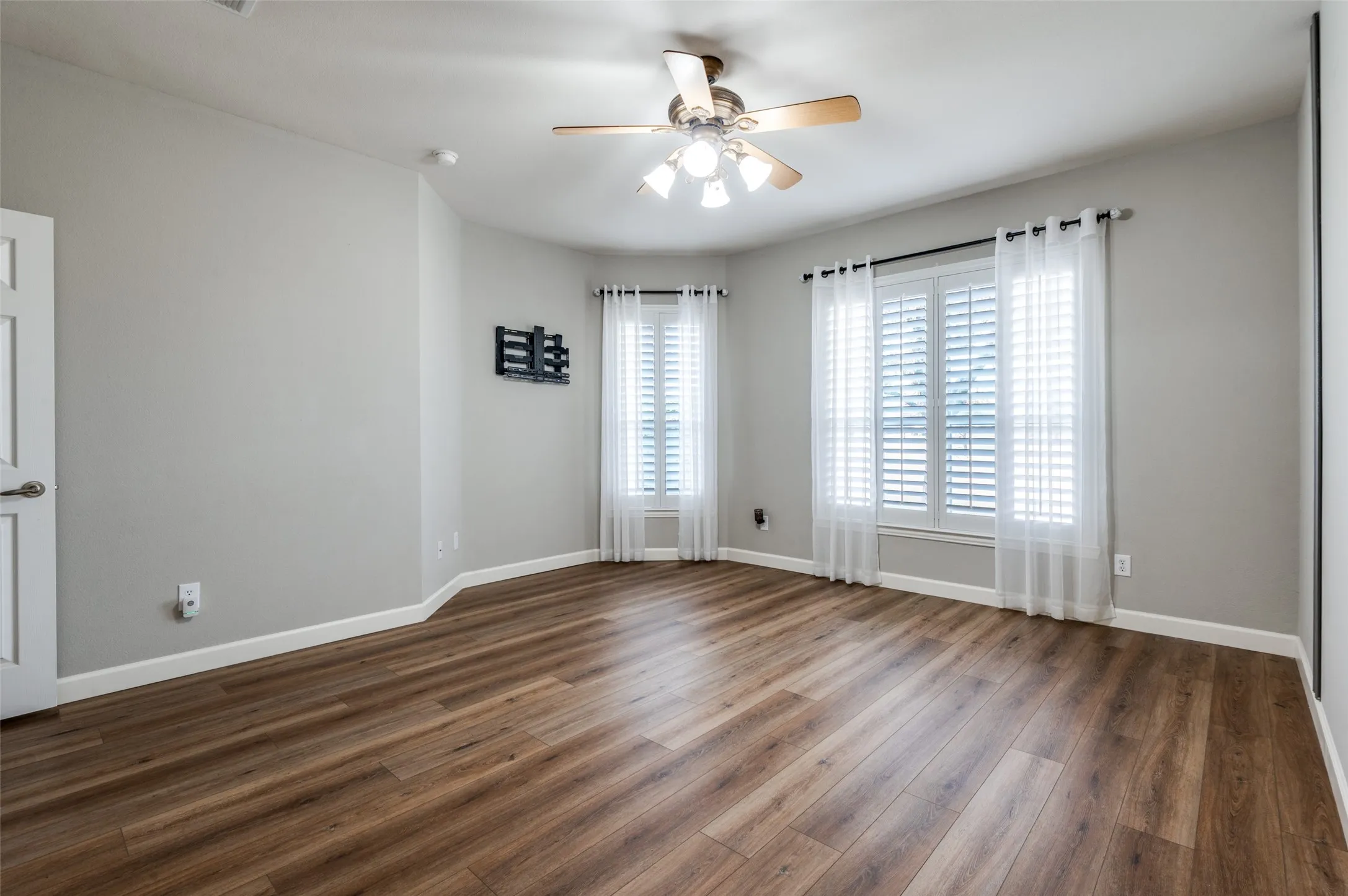 Primary bedroom with dark wood-type flooring and ceiling fan