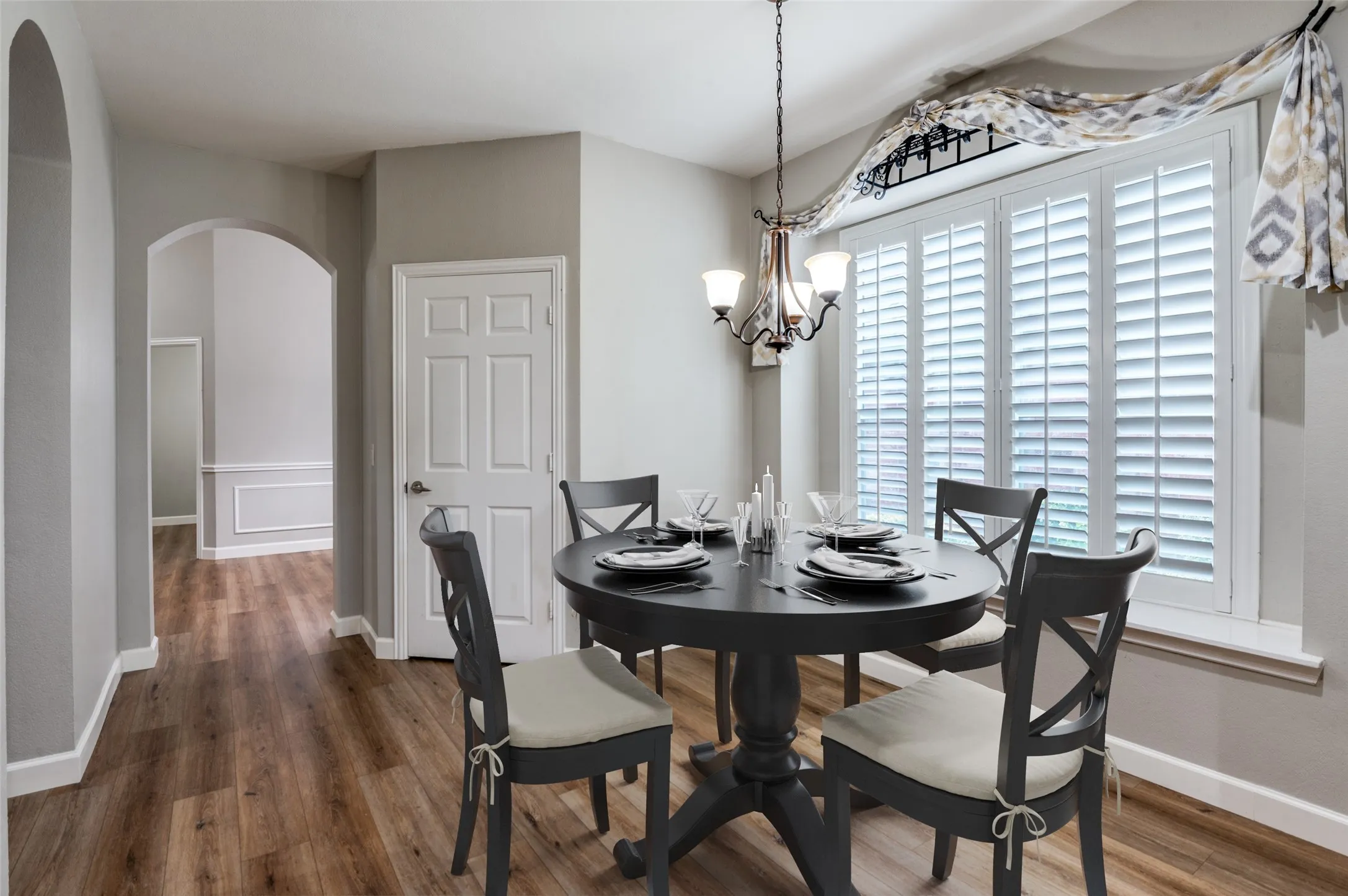 Virtual Staged Breakfast space featuring arched walkways, wood finished floors, and a chandelier