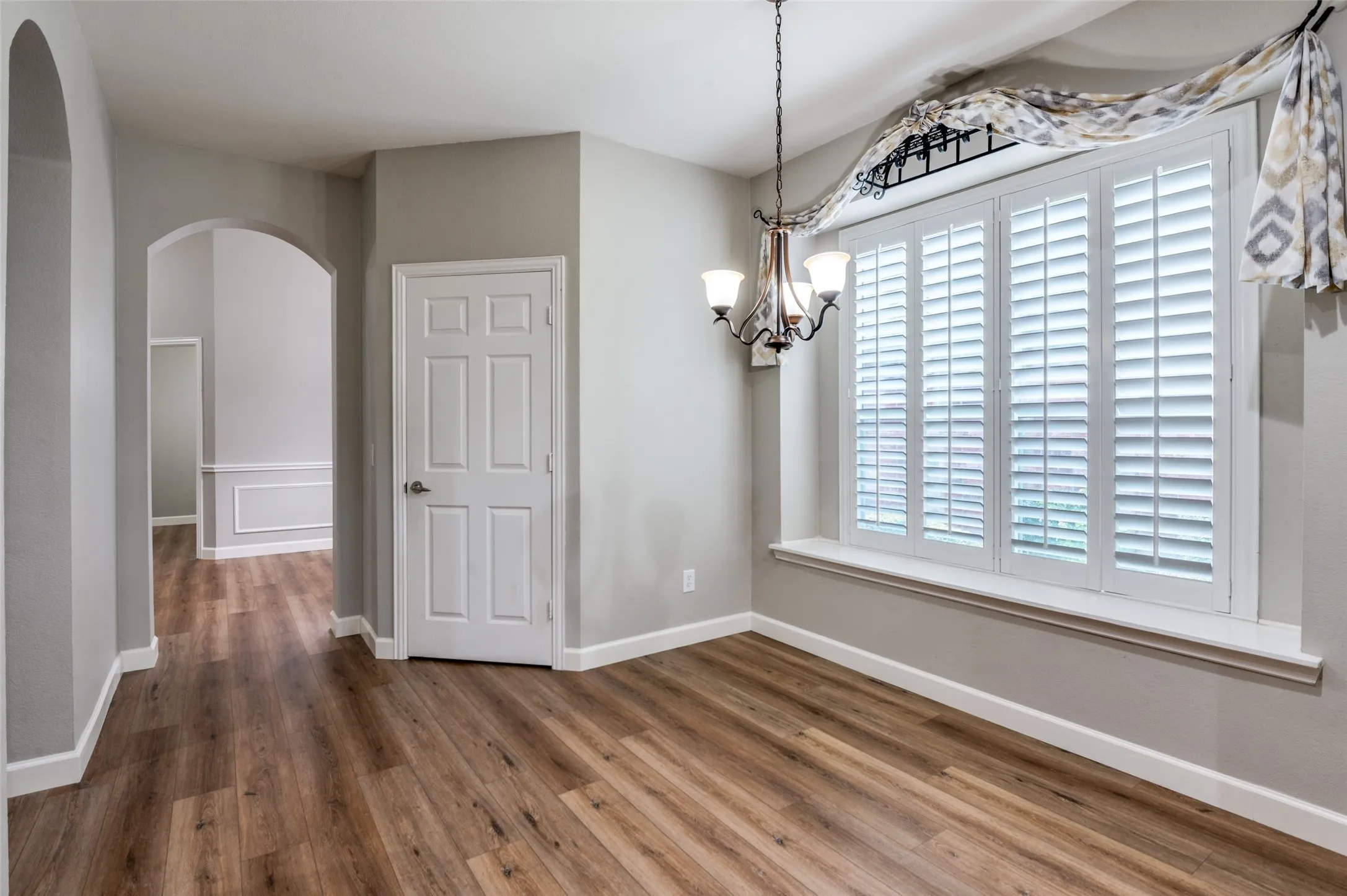 Unfurnished breakfast area featuring arched walkways, wood finished floors, and a chandelier