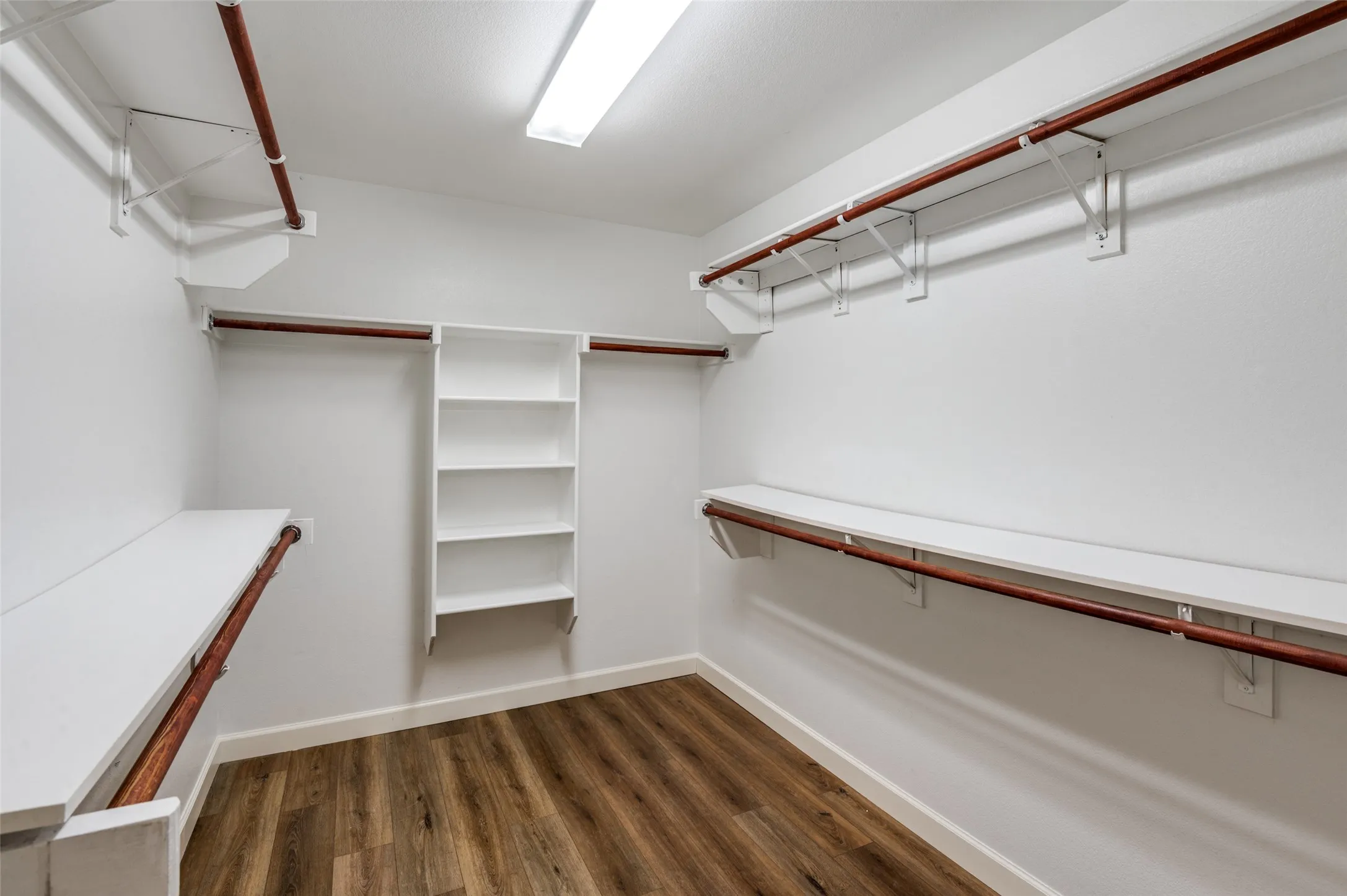 Spacious ensuite closet featuring dark wood finished floors