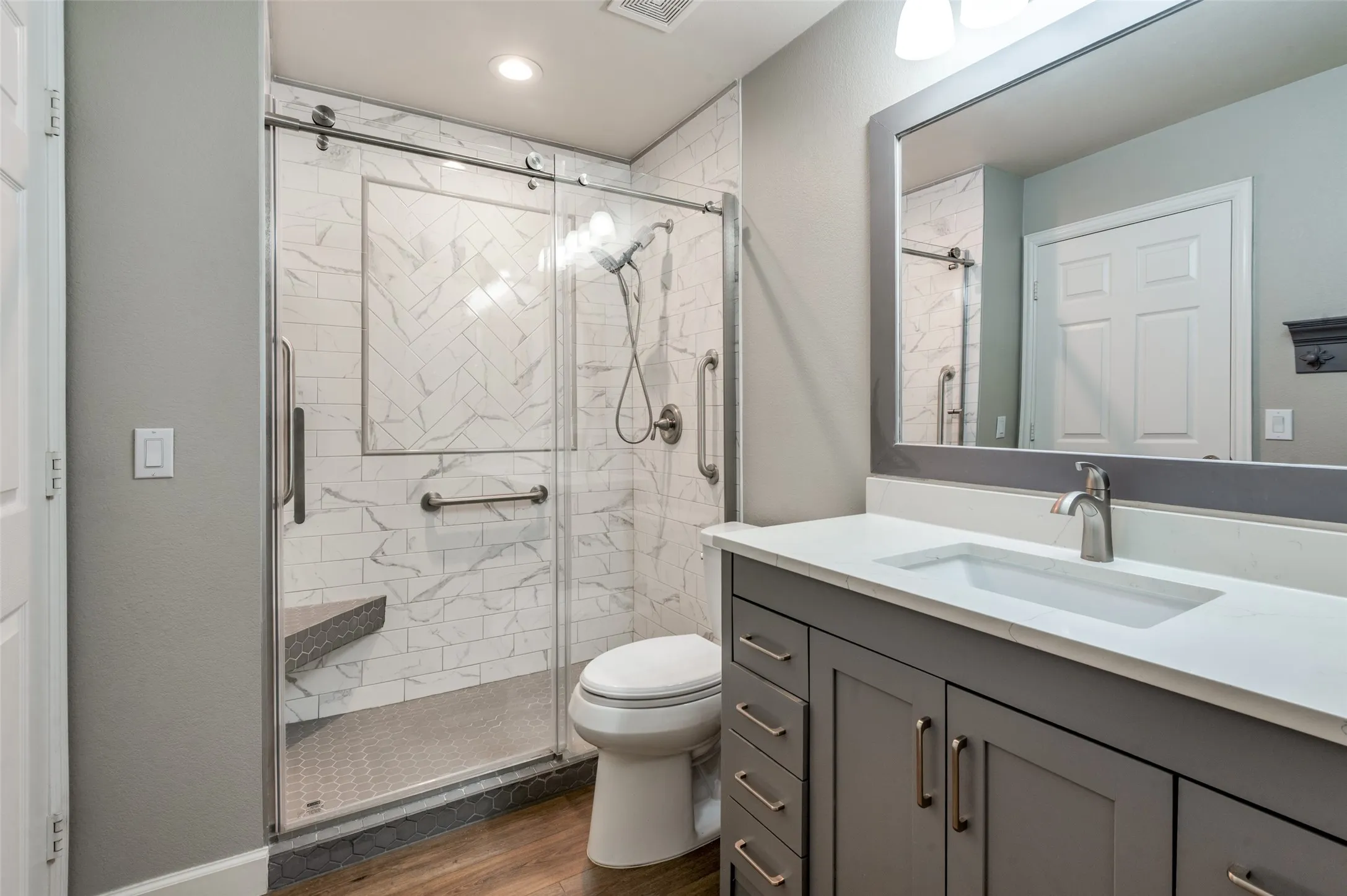 Full guest bath with vanity, dark wood-style floors, and a shower stall