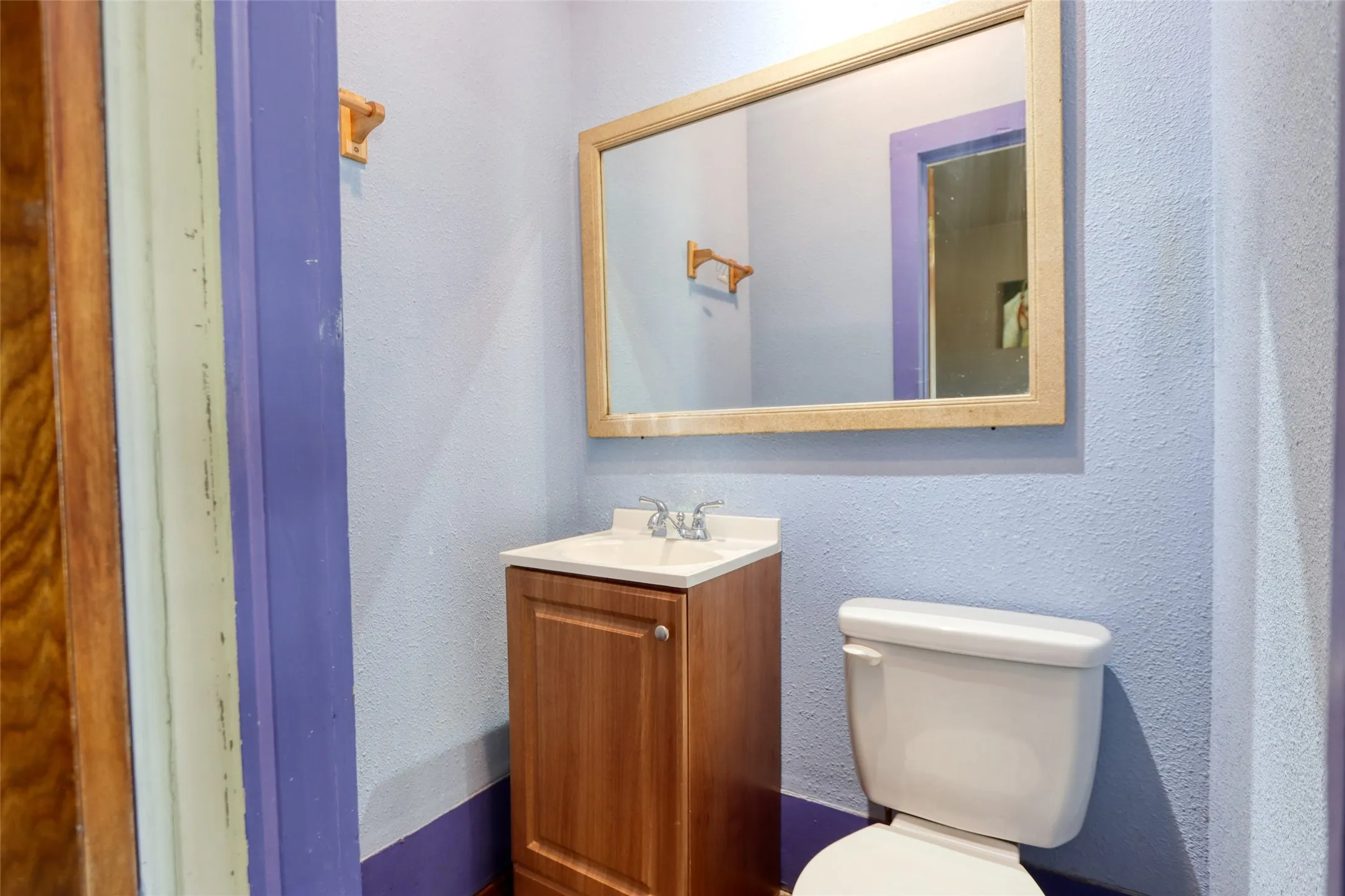 Half bath featuring a textured wall and vanity