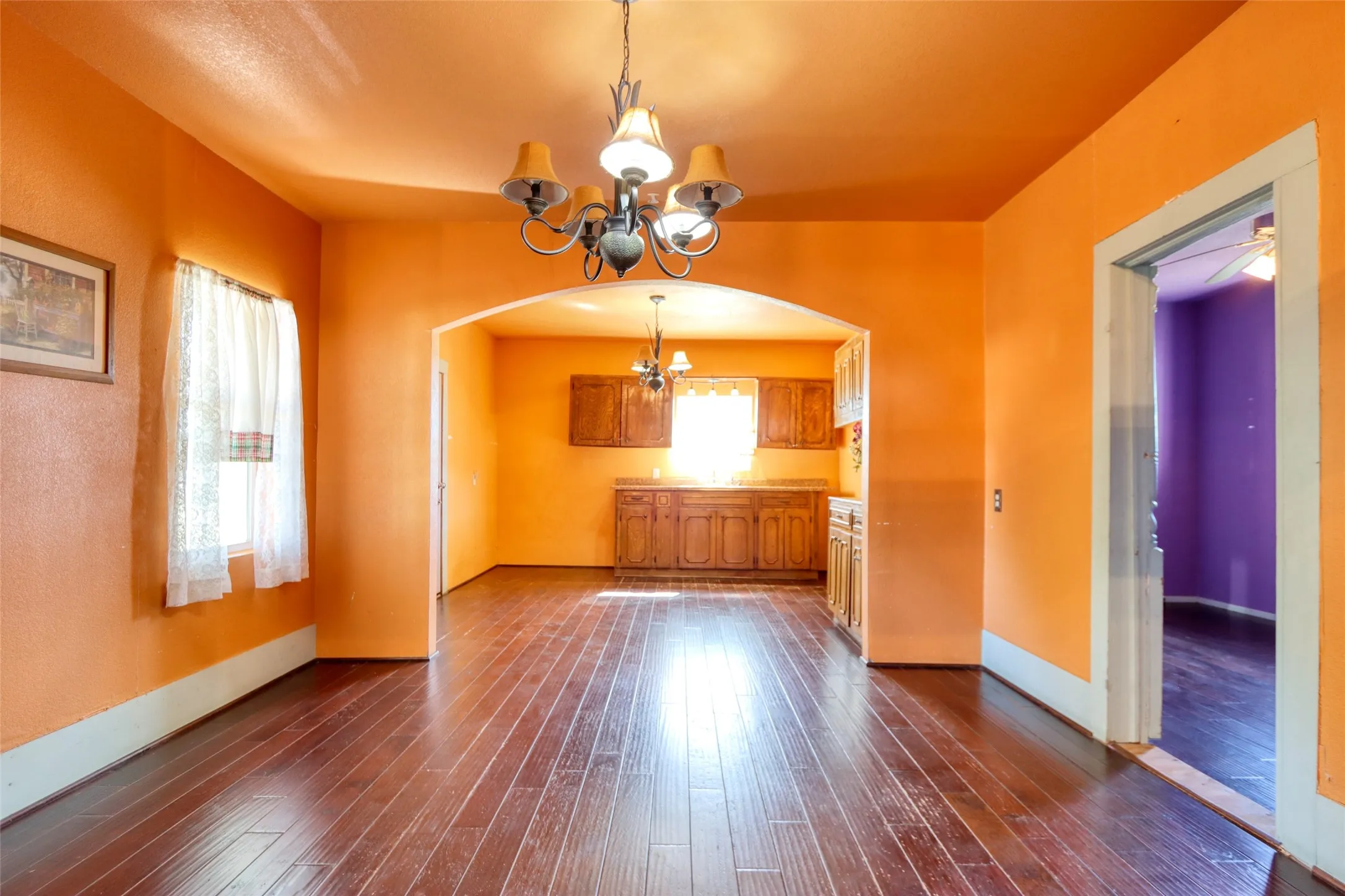 Unfurnished dining area featuring a chandelier, arched walkways, and dark wood-style floors