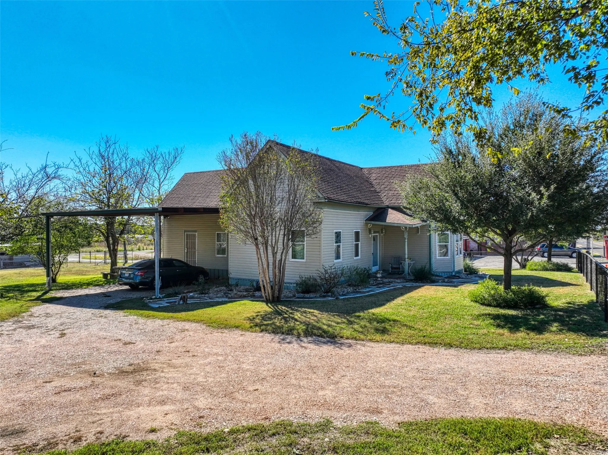 Side View of home featuring a carport, a shingled roof, driveway, and covered porch