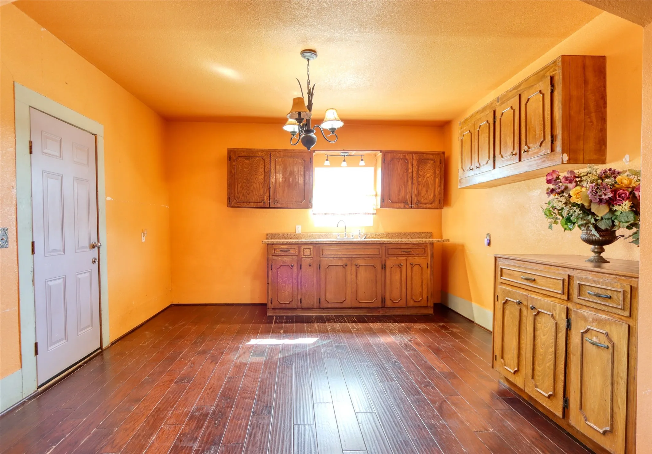Kitchen featuring brown cabinets, light countertops, a chandelier, hanging light fixtures, and a textured ceiling
