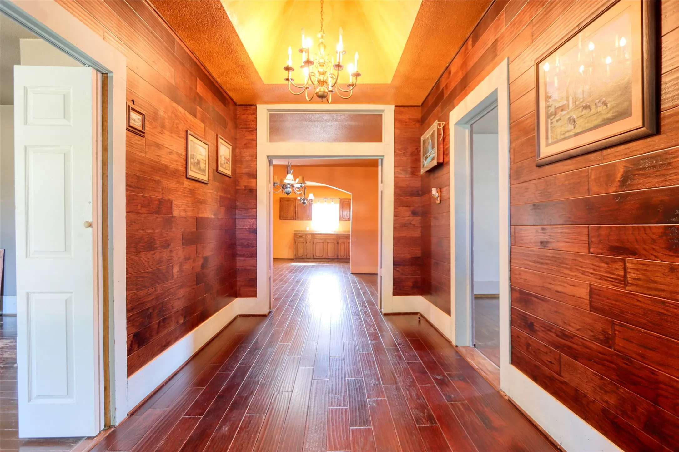 Corridor featuring a chandelier, wood walls, and dark wood-type flooring