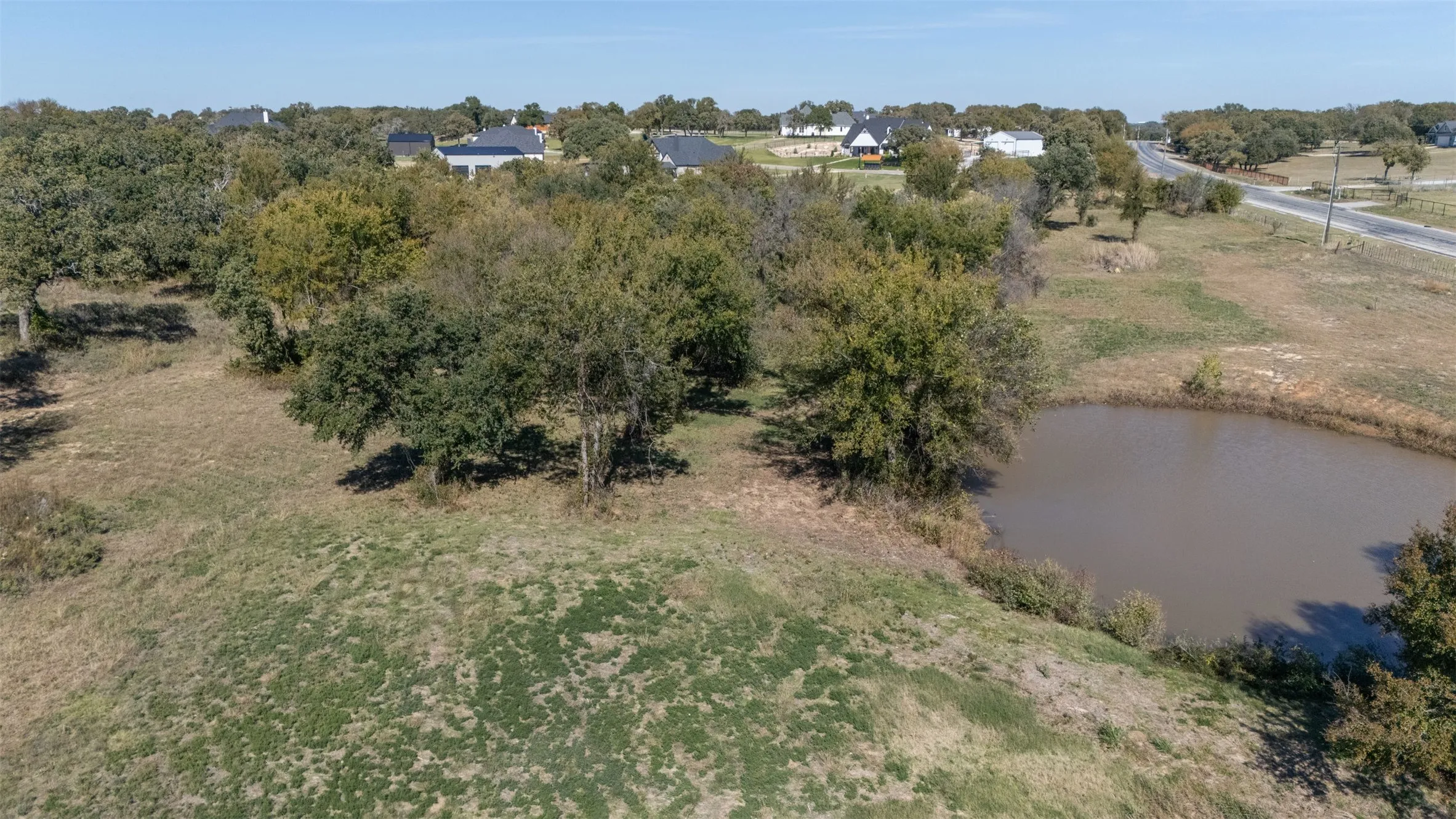 Aerial view of property and surrounding area with a large body of water and a tree filled landscape