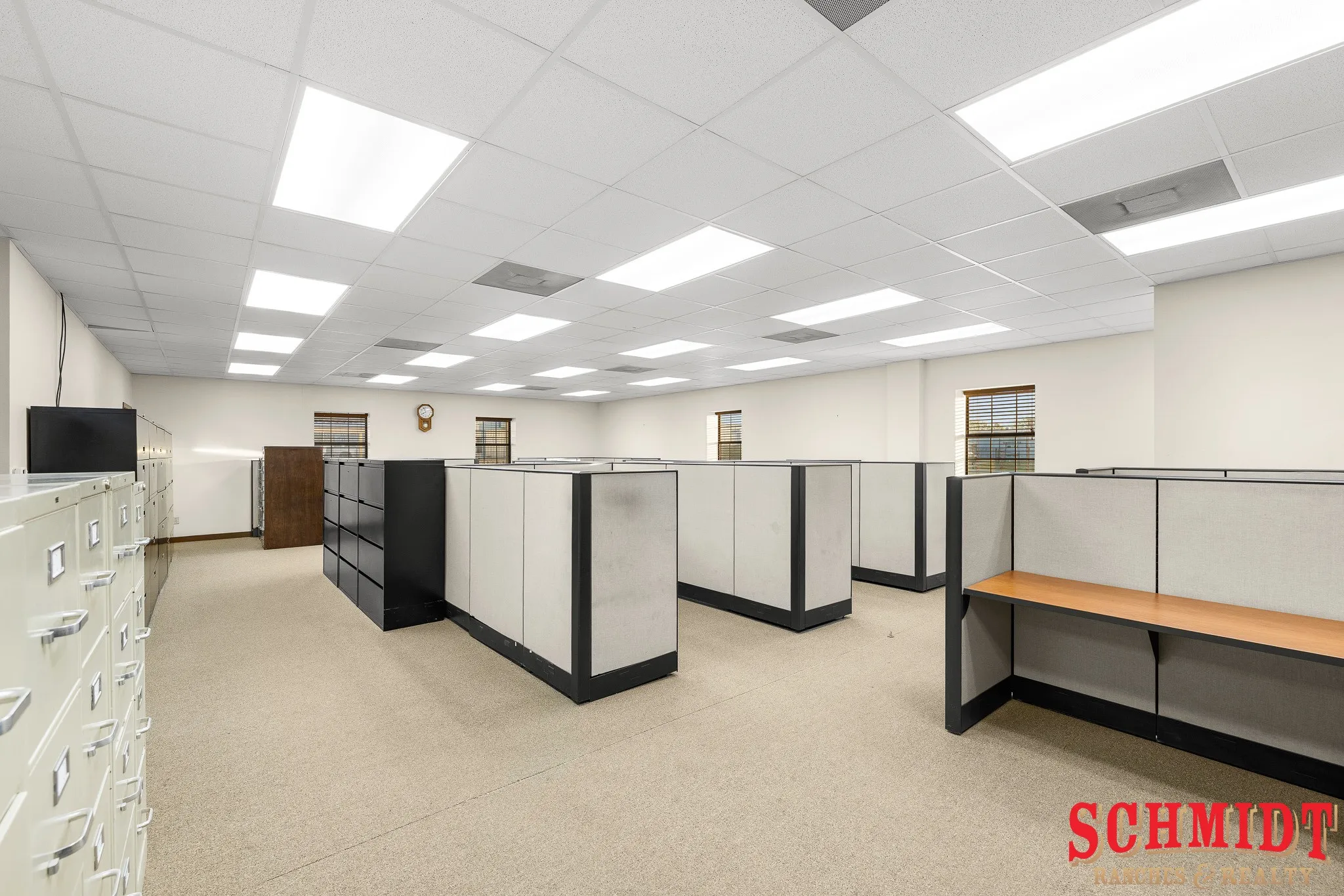 Recessed lighting with drop ceiling tiles, neutral-toned wall paint, and windows with interior trim
