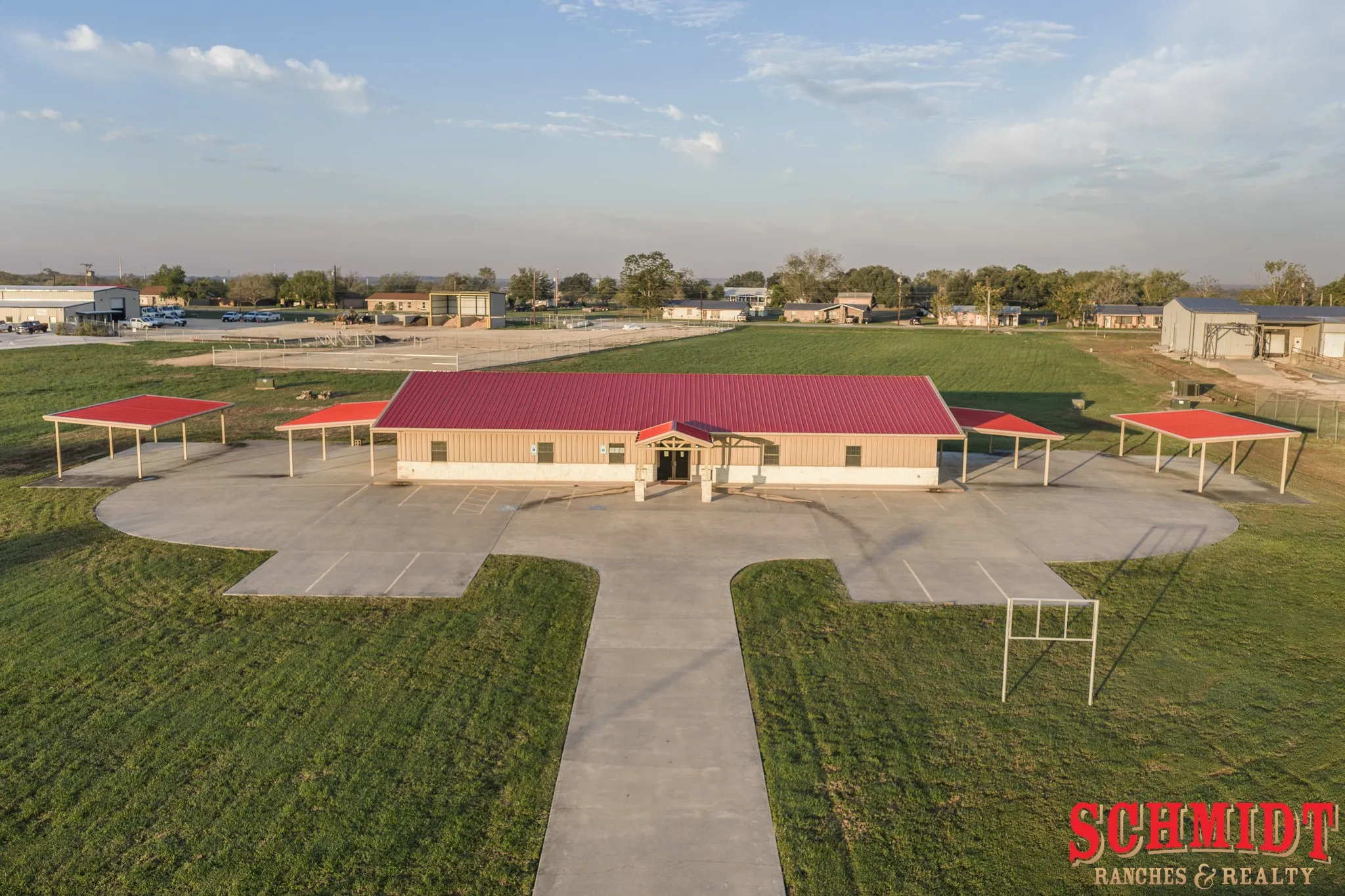 Single-story commercial building featuring a red metal roof and neutral-toned siding