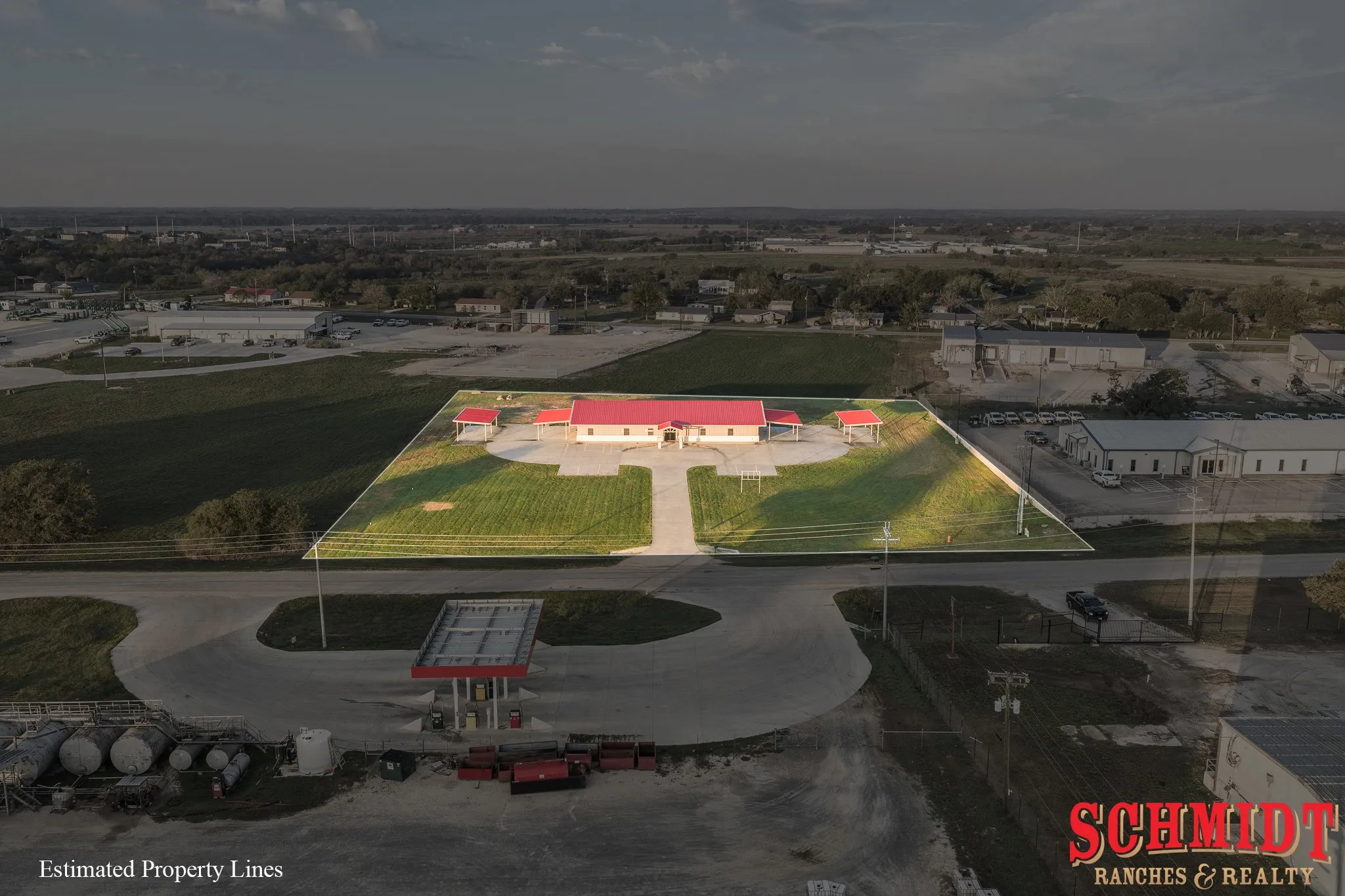 Building with red roof, expansive paved lot, and surrounding green space