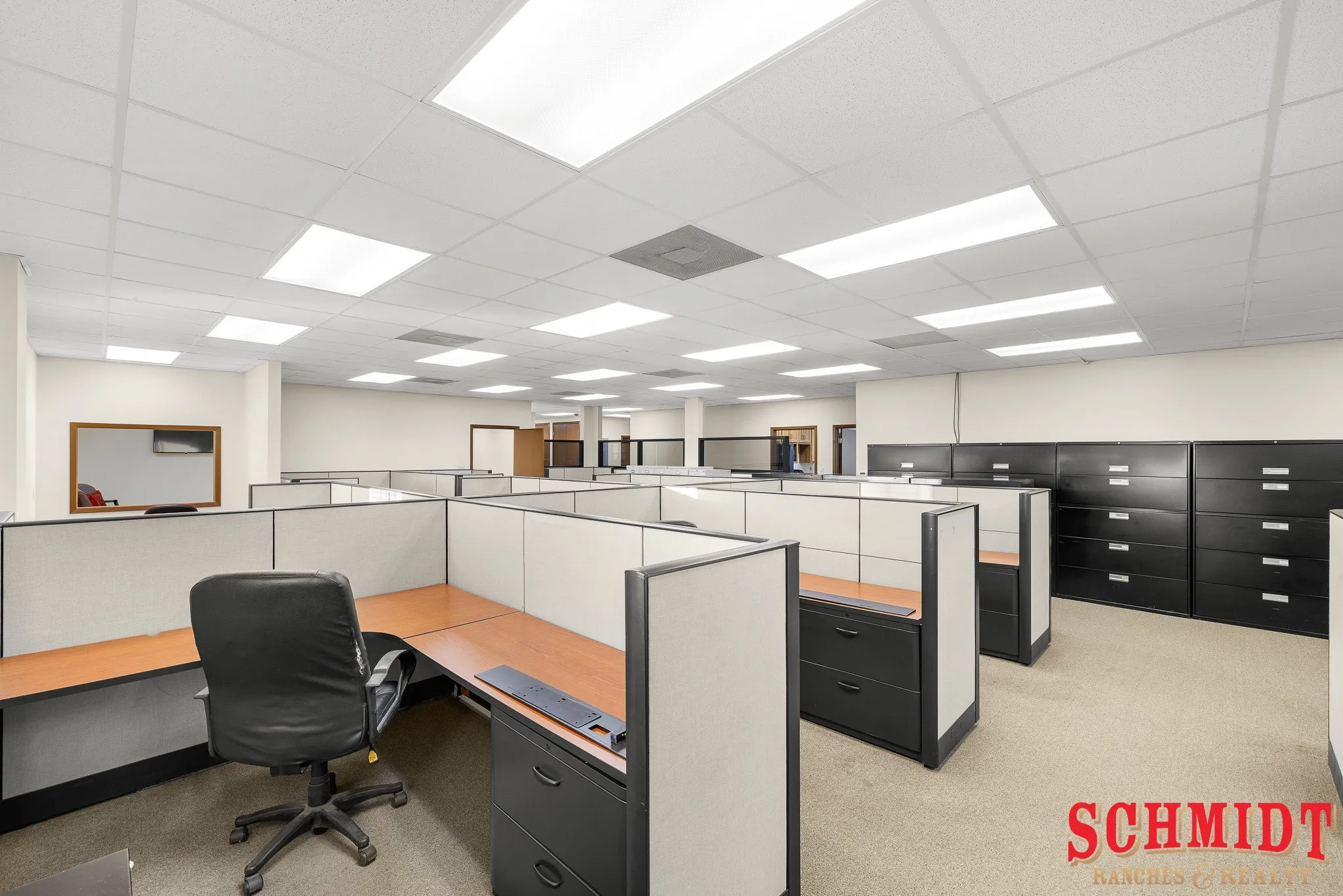 Open-plan office space featuring modular cubicles with wood-finish desks