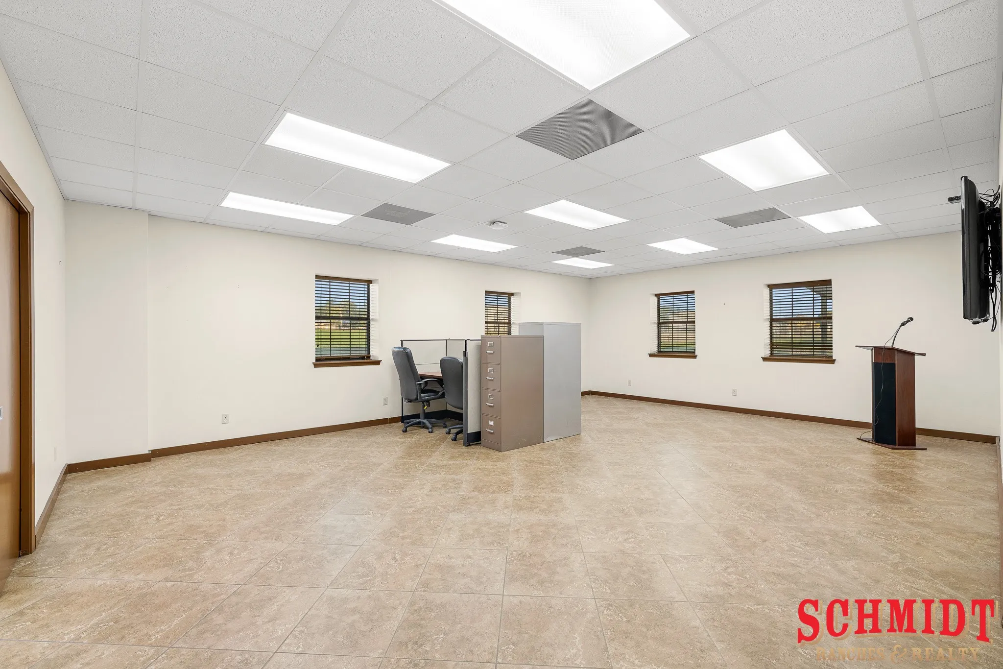 Recessed ceiling lighting, multiple windows with blinds, light-colored walls, and tiled flooring