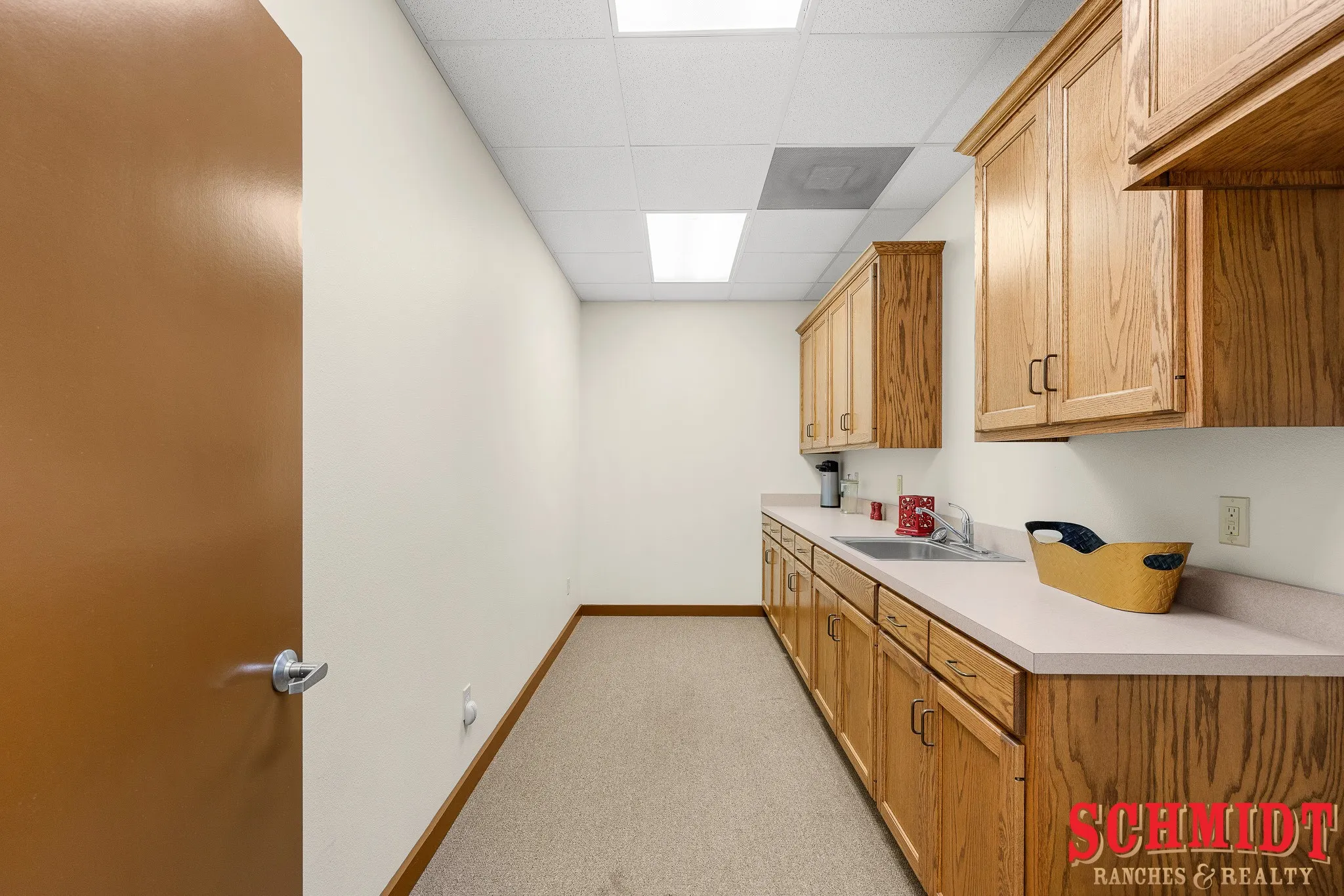 Extensive wood-finish cabinetry, solid surface countertops, stainless steel sink, and recessed lighting