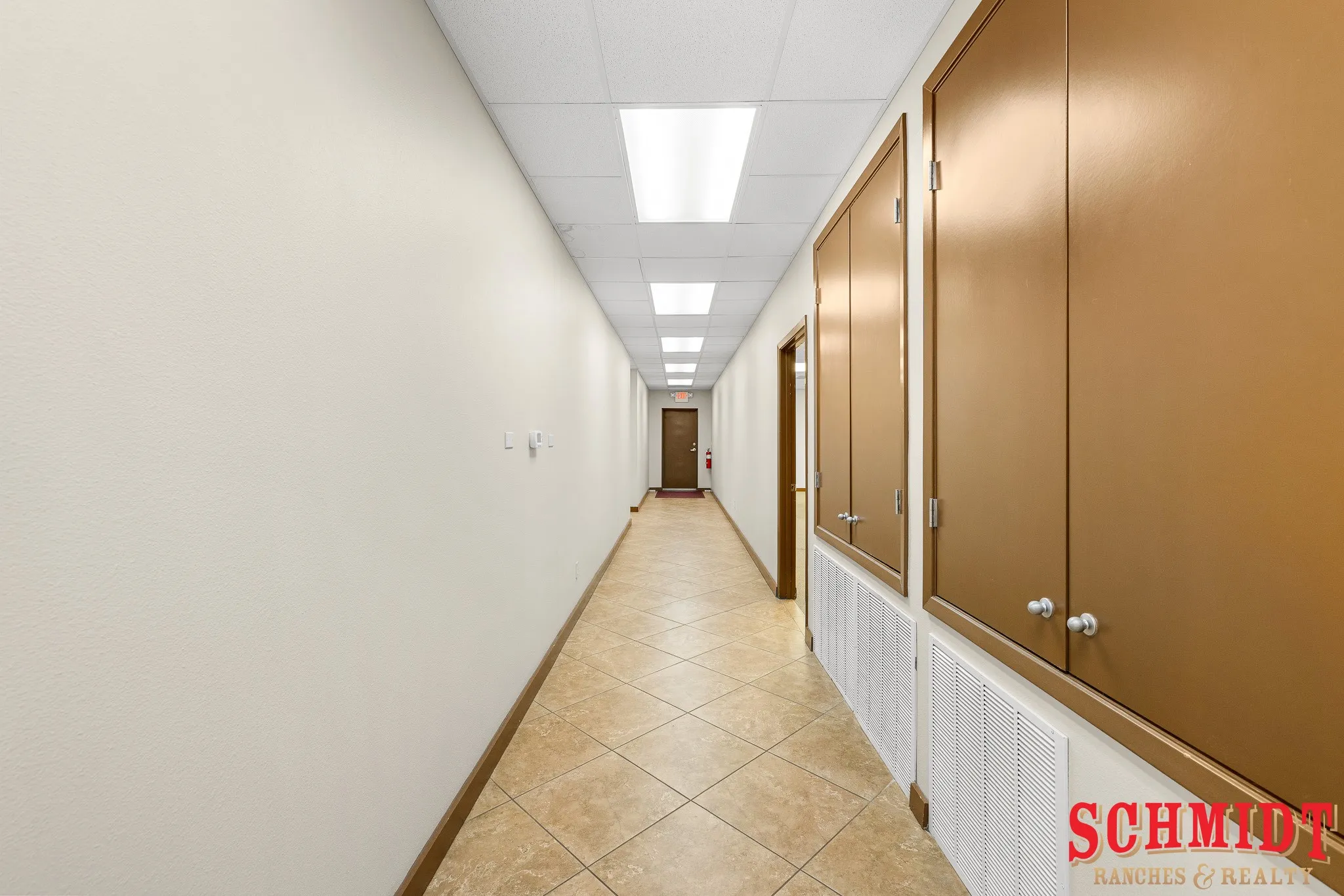 Hallway with recessed lighting, wall-mounted storage cabinets, light-toned textured walls, and diagonal tile flooring