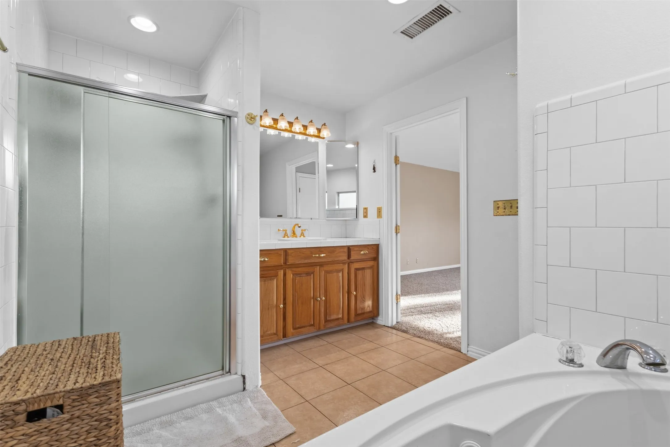 Full bathroom featuring light tile patterned floors, a garden tub, vanity, a stall shower, and recessed lighting