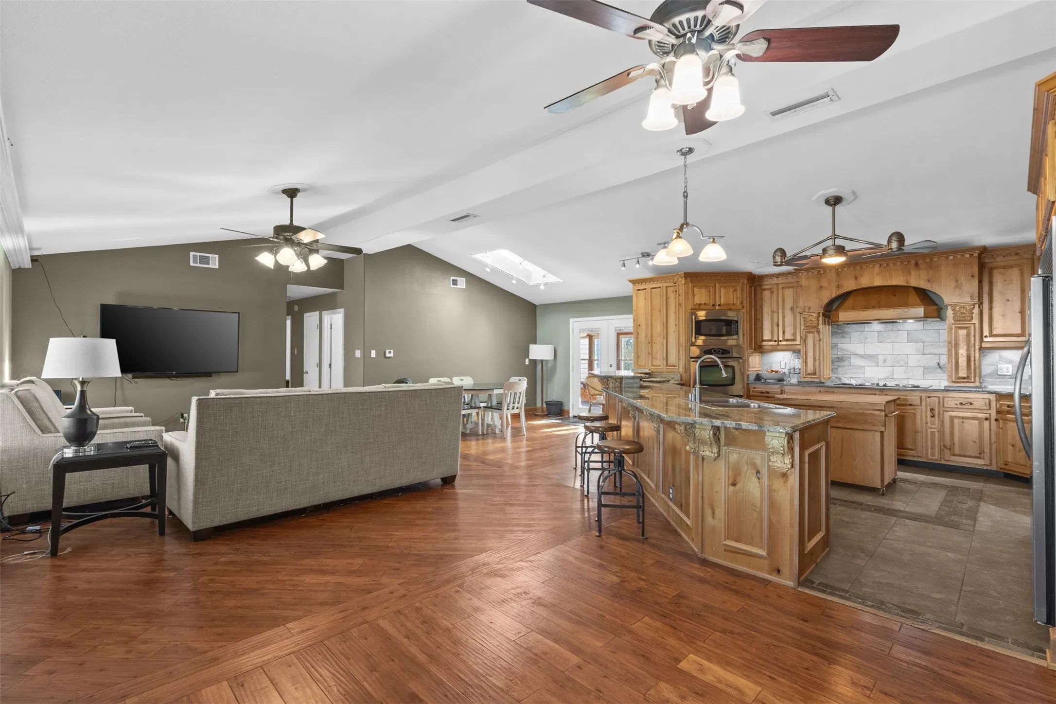 Kitchen with open floor plan, vaulted ceiling, a ceiling fan, a breakfast bar, and backsplash