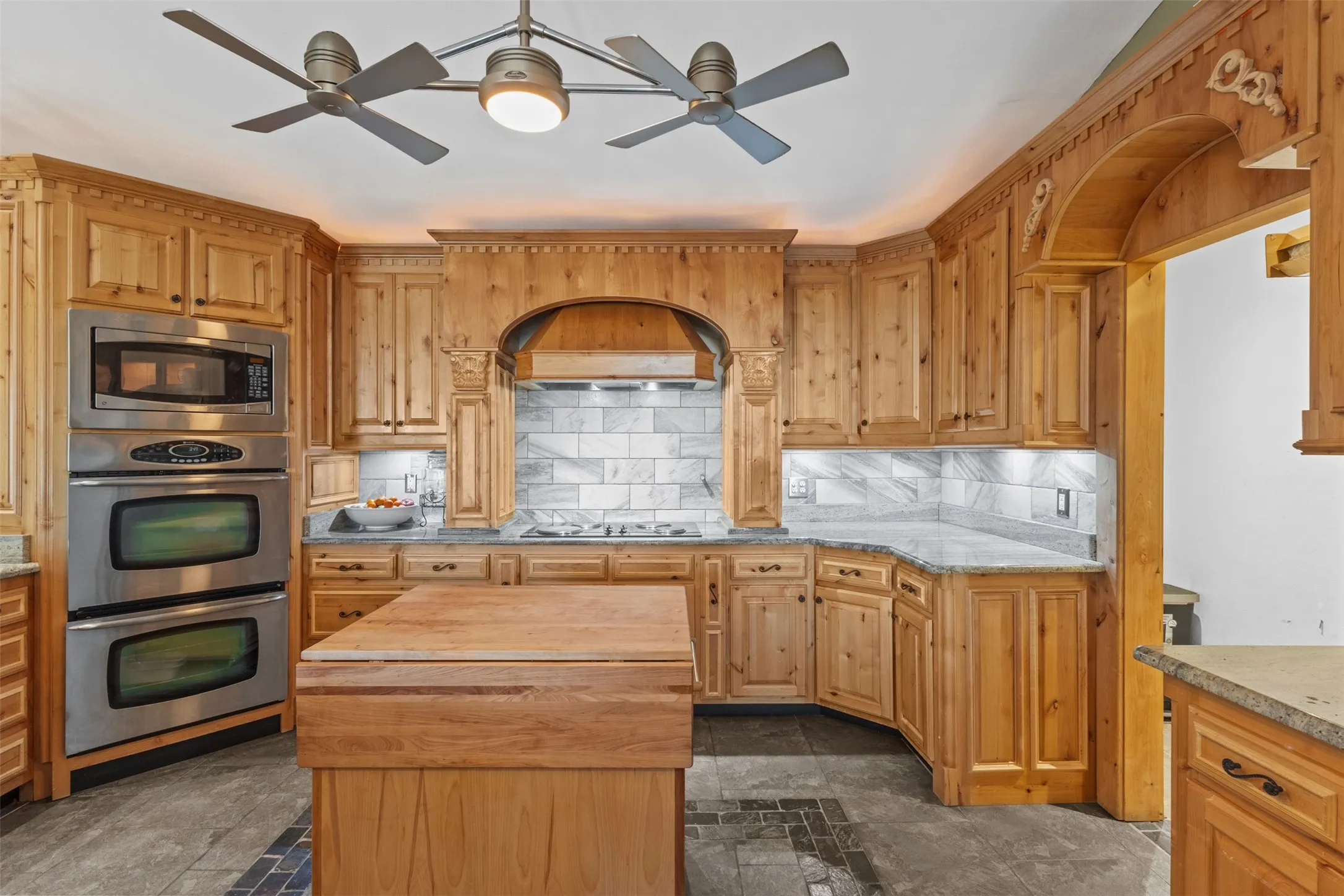Kitchen featuring tasteful backsplash, appliances with stainless steel finishes, a ceiling fan, and butcher block countertops