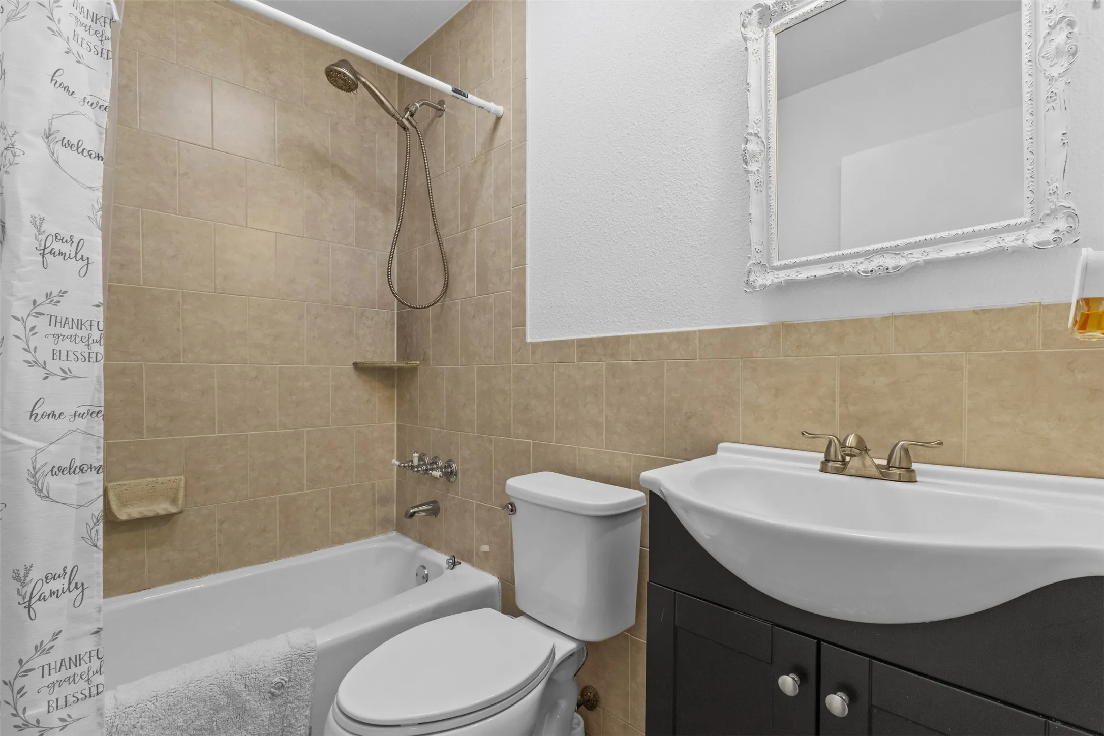 Full bath with vanity, shower / bath combo with shower curtain, tile walls, and a textured wall
