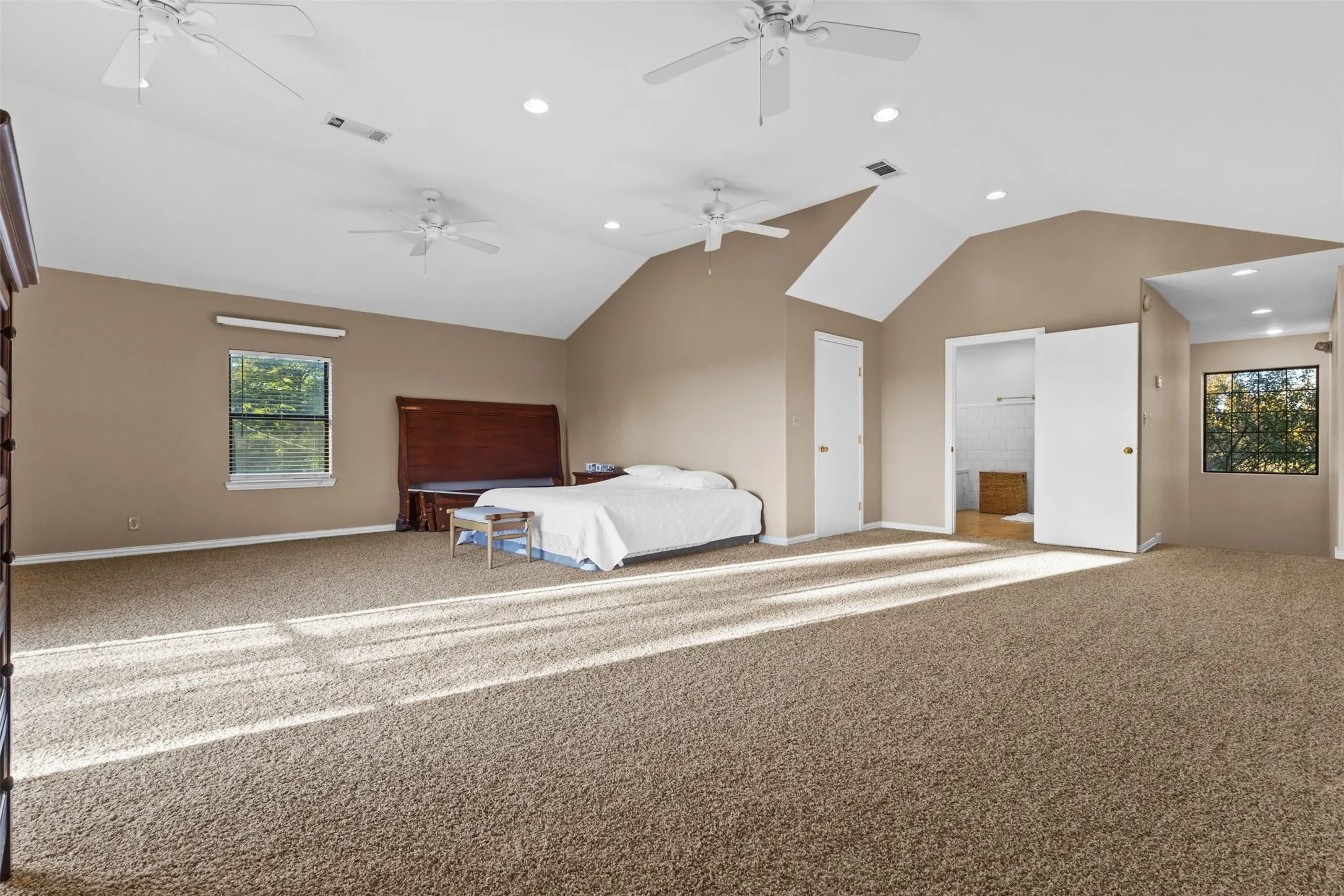 Unfurnished bedroom featuring carpet flooring, recessed lighting, lofted ceiling, ensuite bathroom, and a ceiling fan