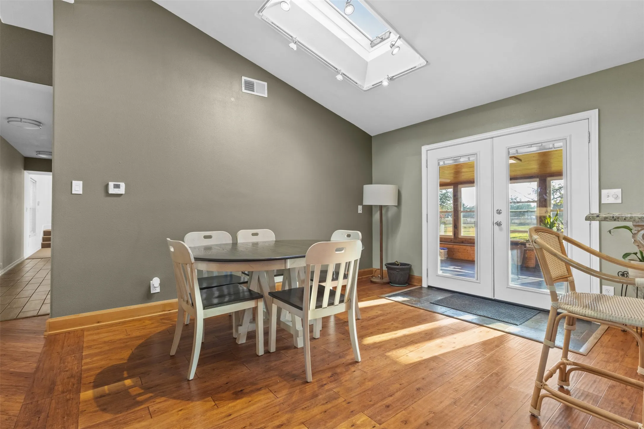 Dining space featuring a skylight, hardwood / wood-style flooring, vaulted ceiling, and french doors