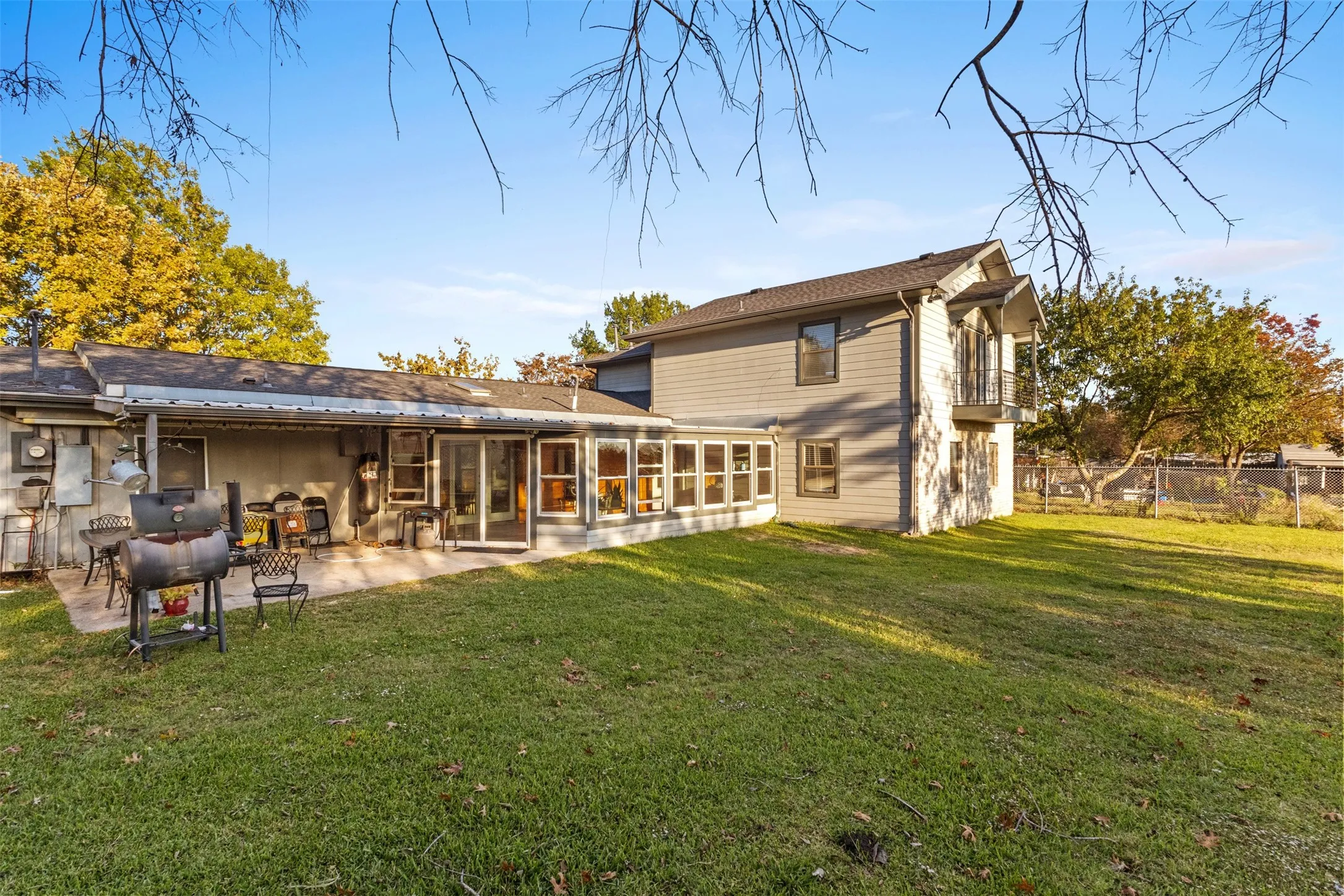 Back of house with a sunroom and a patio