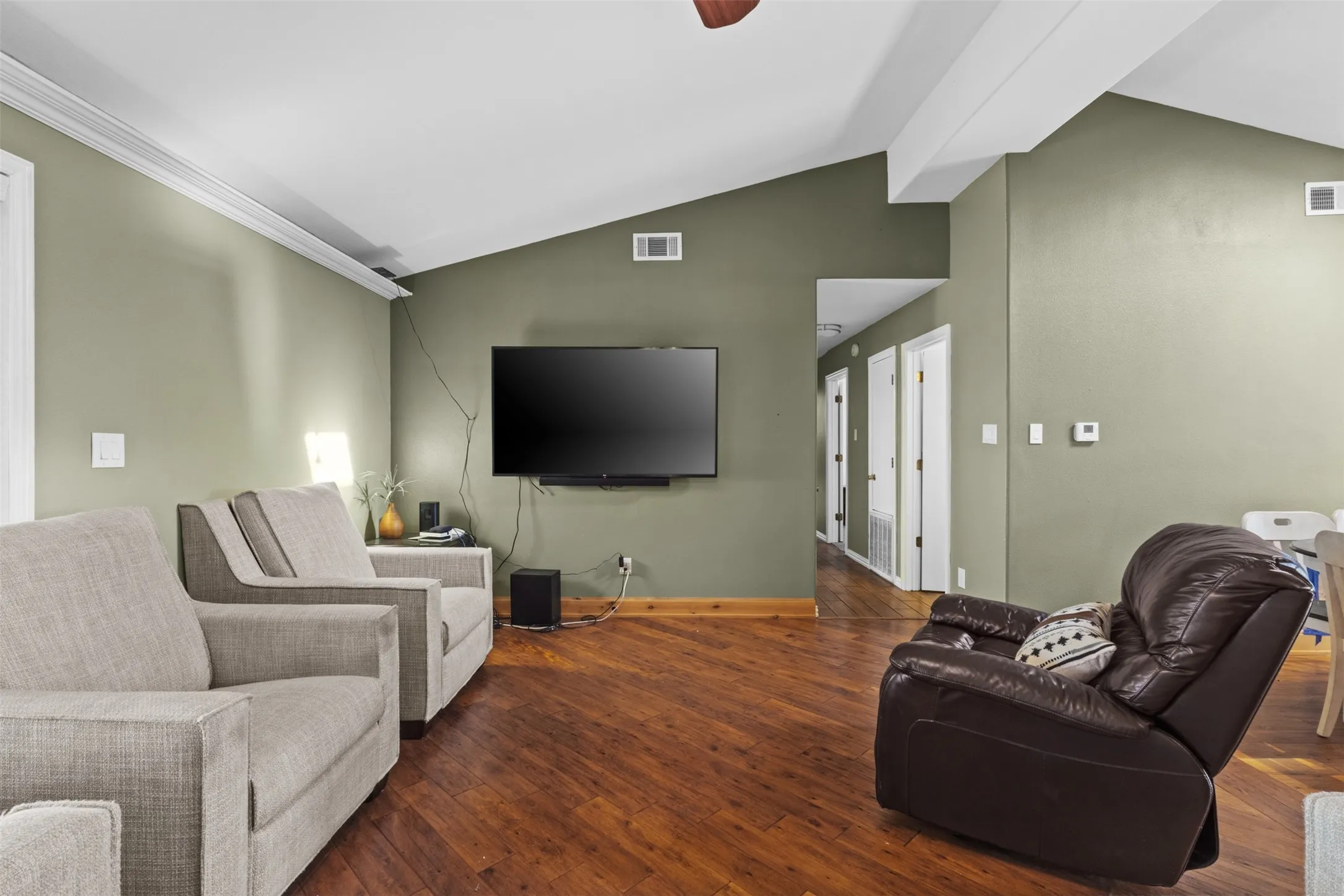 Living area featuring vaulted ceiling, wood-type flooring, a ceiling fan, and ornamental molding