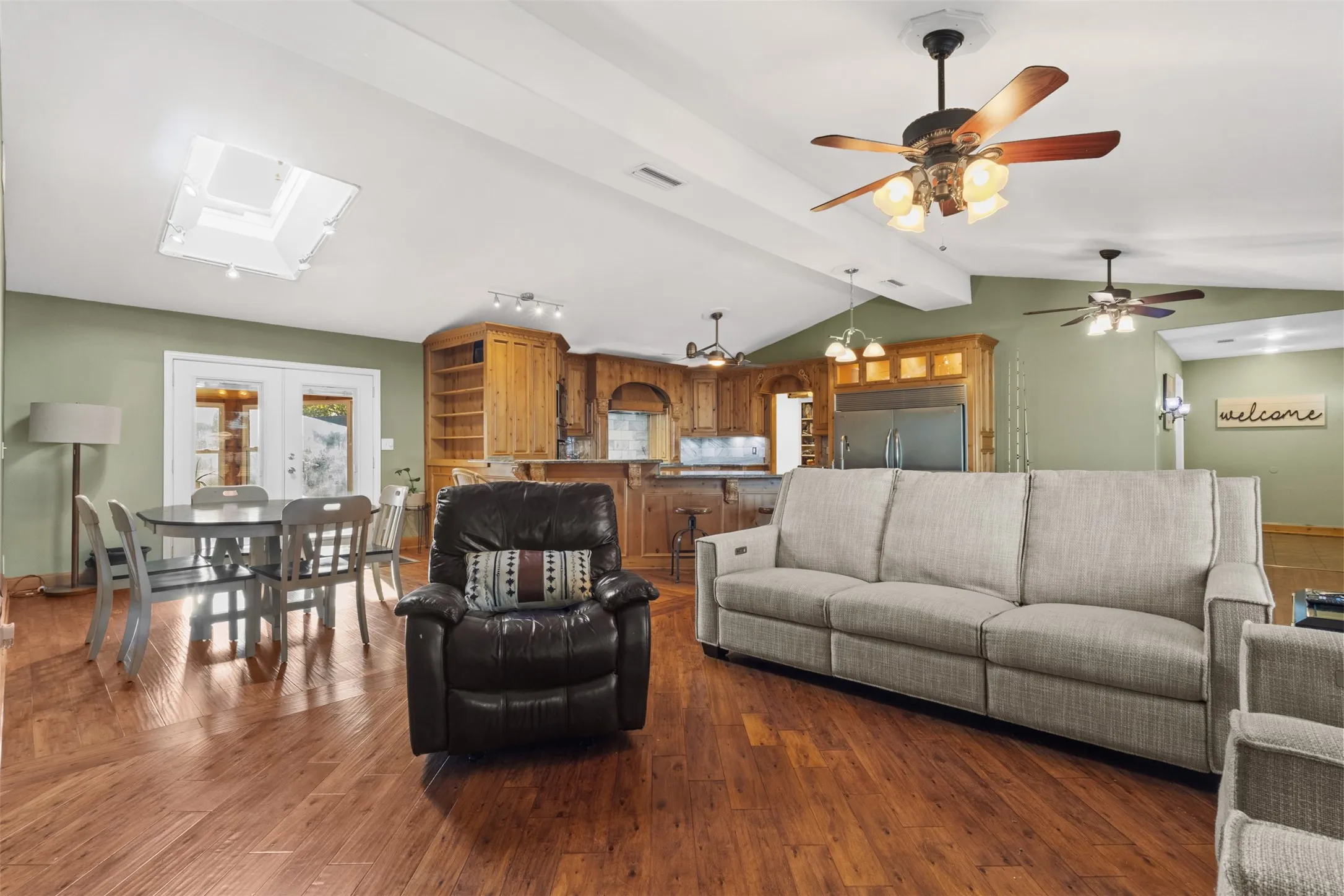 Living area with wood finished floors, a skylight, and french doors